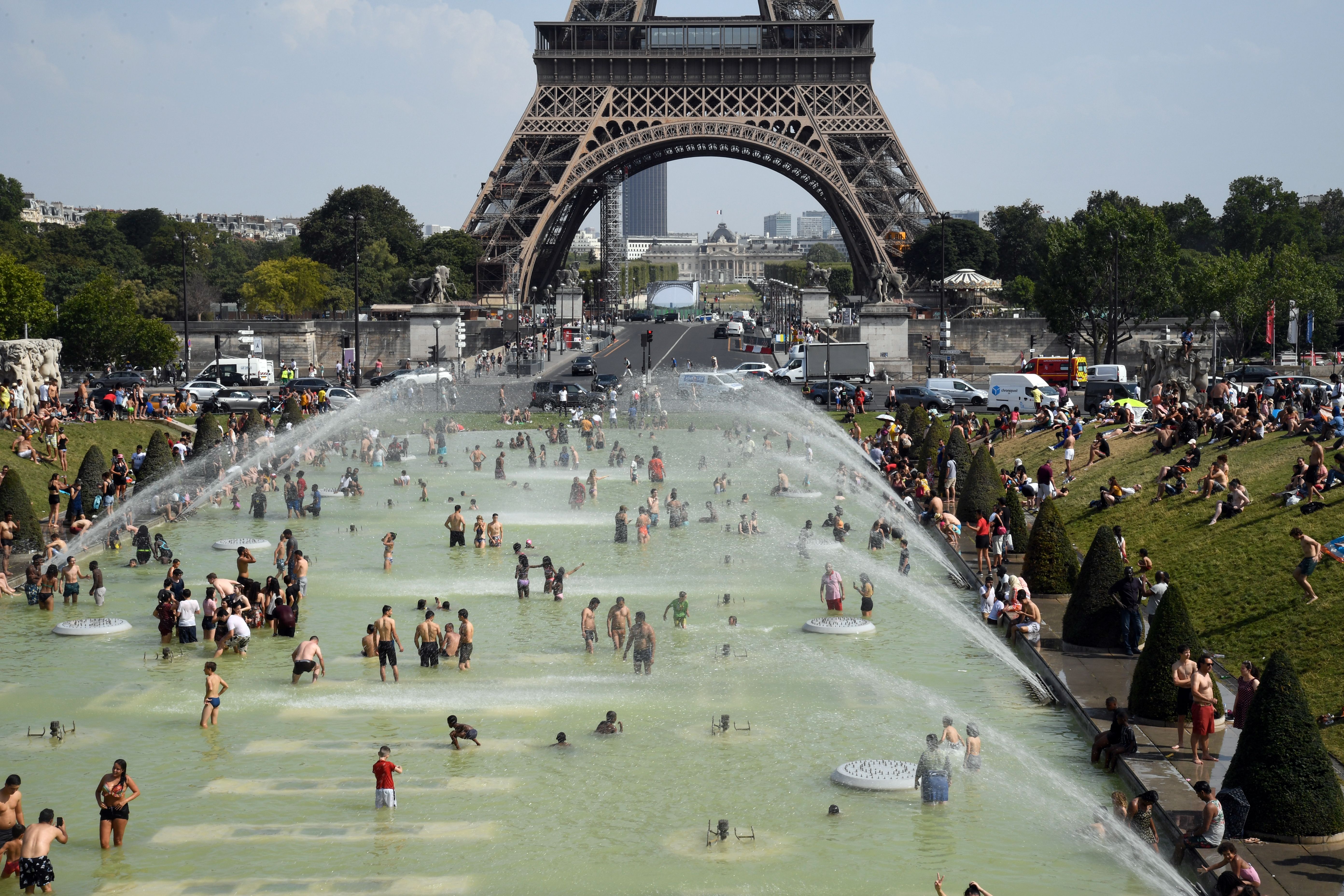 People cool off and sunbathe at the Trocadero Fountains in Paris on July 25, 2019 as a heat wave hits the French capital. 