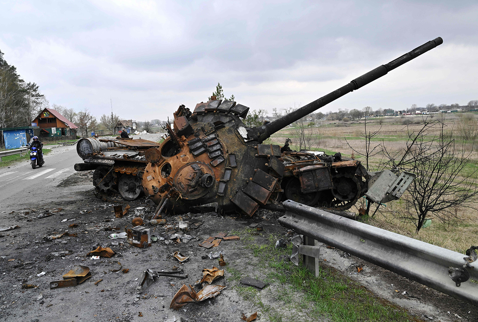 A man rides a motorbike past a destroyed Russian tank on a road in the Kyiv region on April 16.