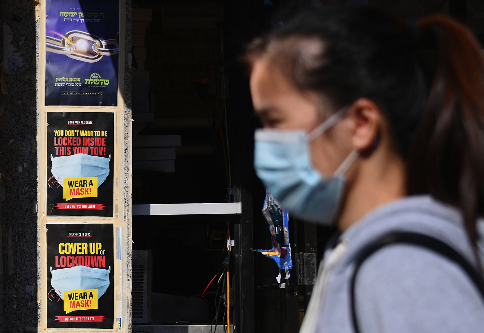People walk past closed stores in the Borough Park section of Brooklyn, one of the five boroughs of New York City, on October 9.
