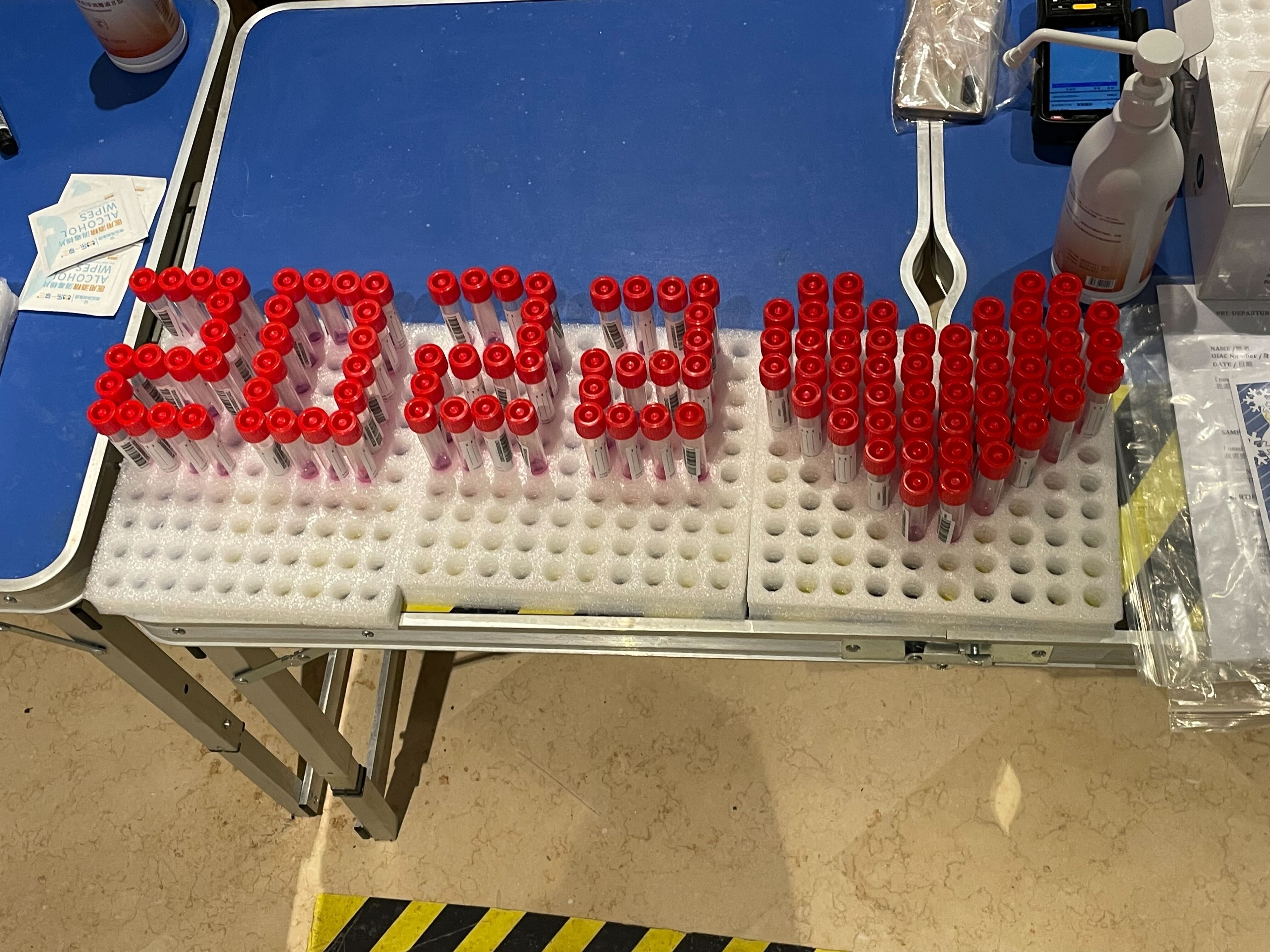 Testing vials arranged to read "2022" and a heart shape, at a Covid-19 testing station inside the Beijing Olympic bubble.