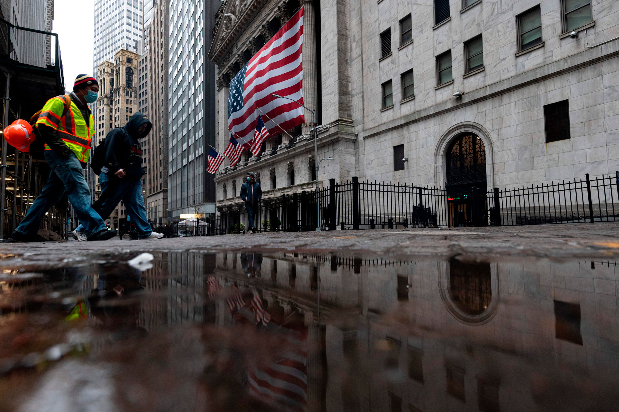 Two men wearing masks walks pass the New York Stock Exchange (NYSE) on April 30, in New York City.
