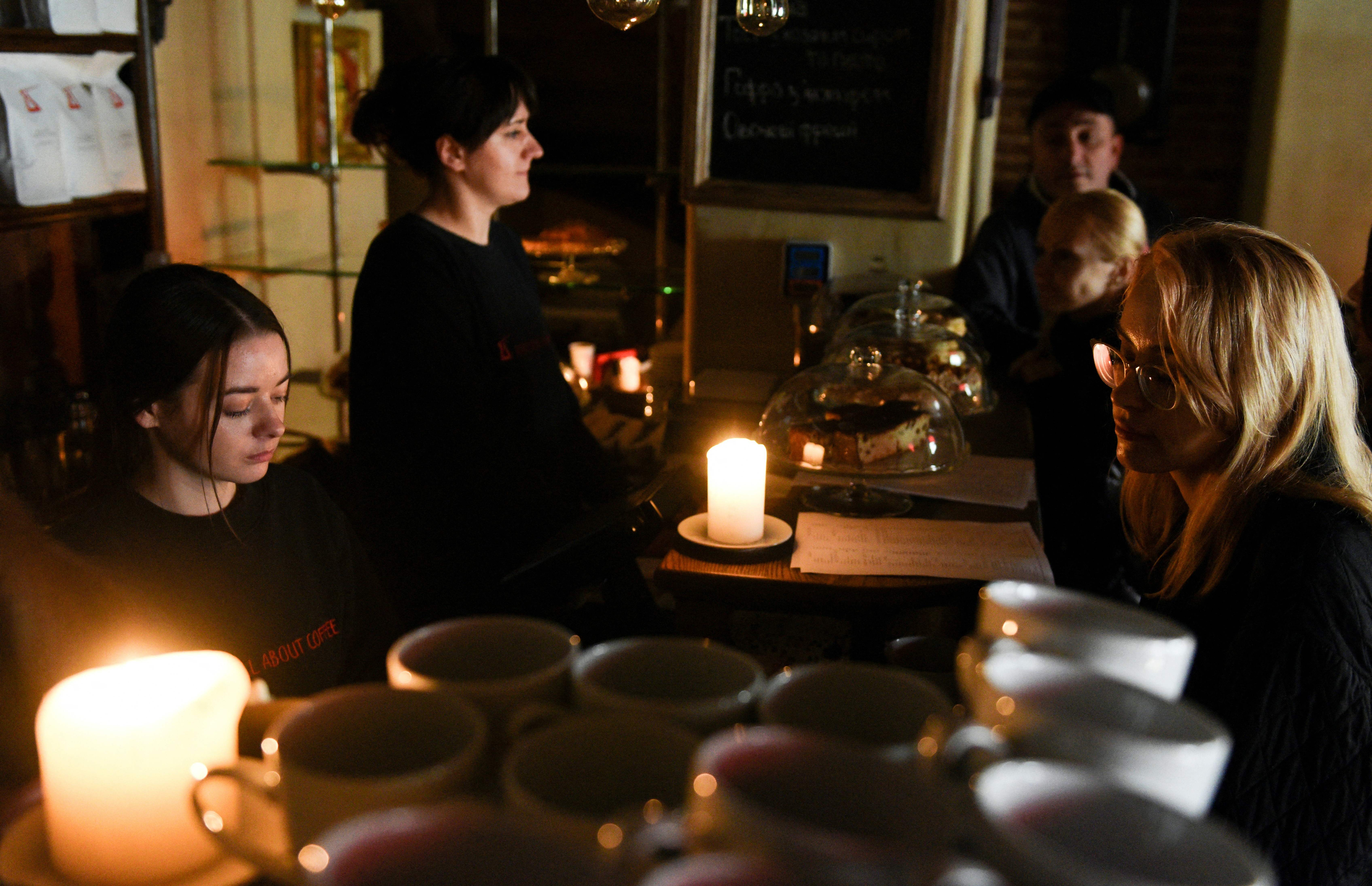 Employees of a cafe serve visitors in a cafe without electricity in Lviv, after three Russian missiles fired targeted energy infrastructure on October 11.