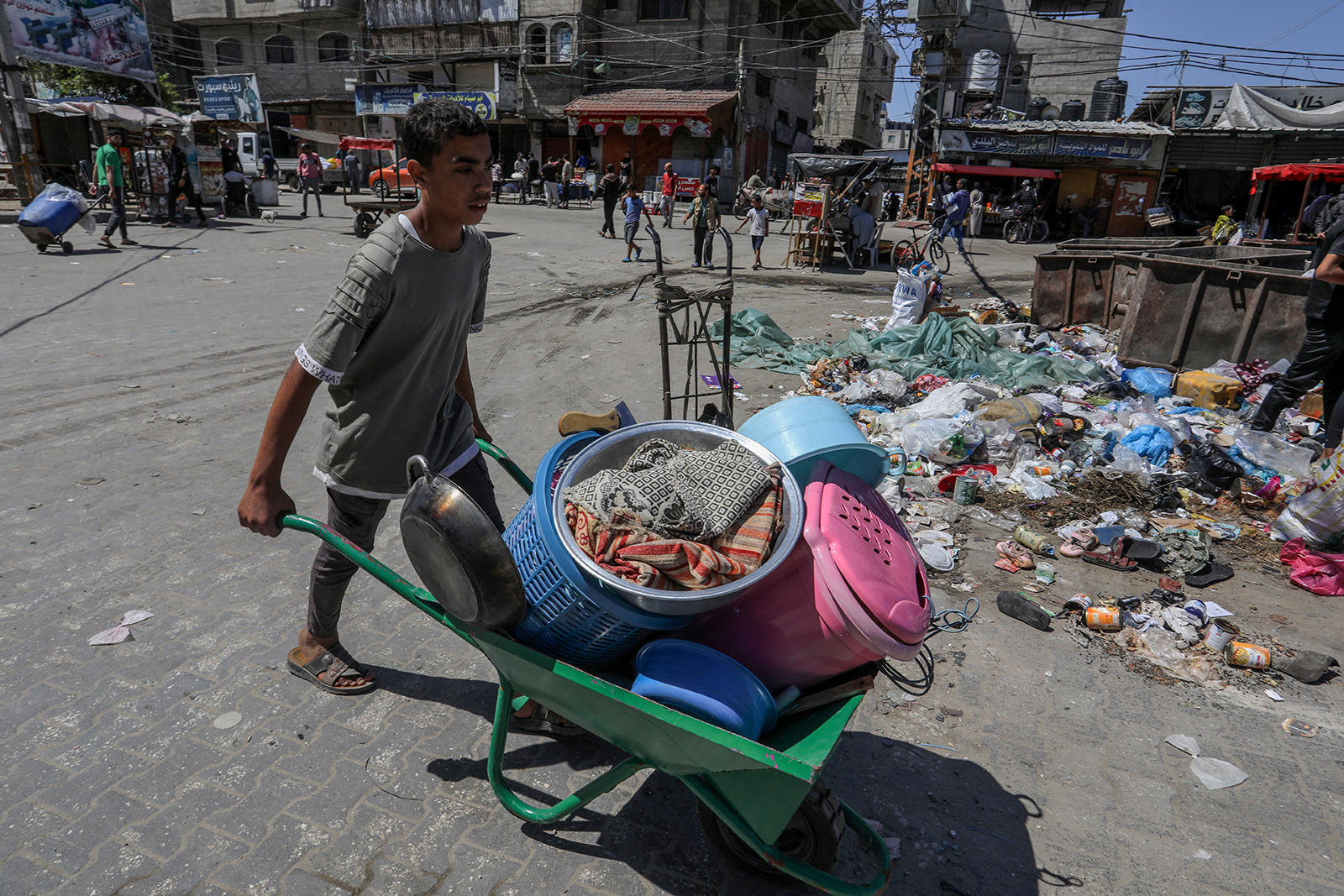 A Palestinian boy pushes a wheelbarrow loaded with personal belongings as he flees following Israeli airstrikes on Al-Geneina and Al-Salam neighborhoods in Rafah on May 8.