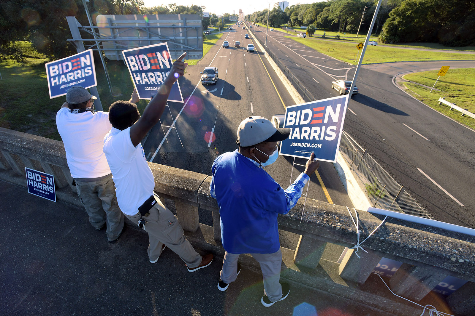 Supporters of presidential candidate Joe Biden try to get the attention of commuters leaving downtown Jacksonville, Florida from an overpass with under three hours before the polls close on Election Day.