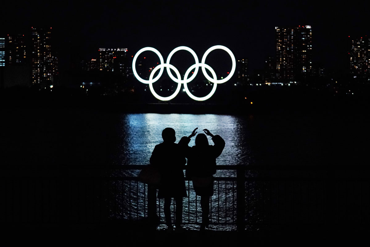 A man and a woman look at the floating Olympic rings along Tokyo Bay on December 1.