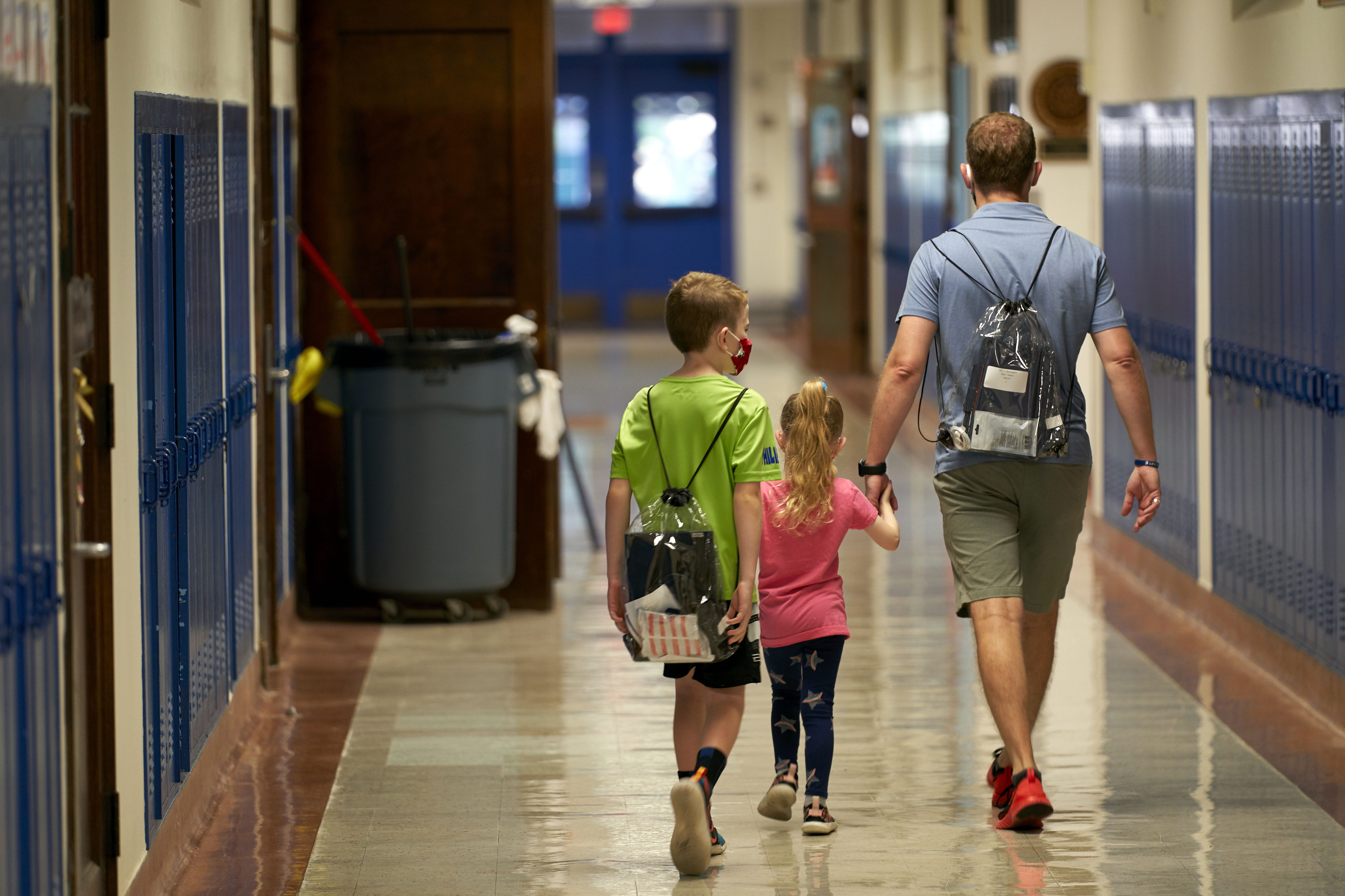 A student and parent wear backpacks carrying a Google Chromebook laptop and an Apple iPad for remote learning during a technology deployment event at Mockingbird Elementary School in Dallas on August 19.