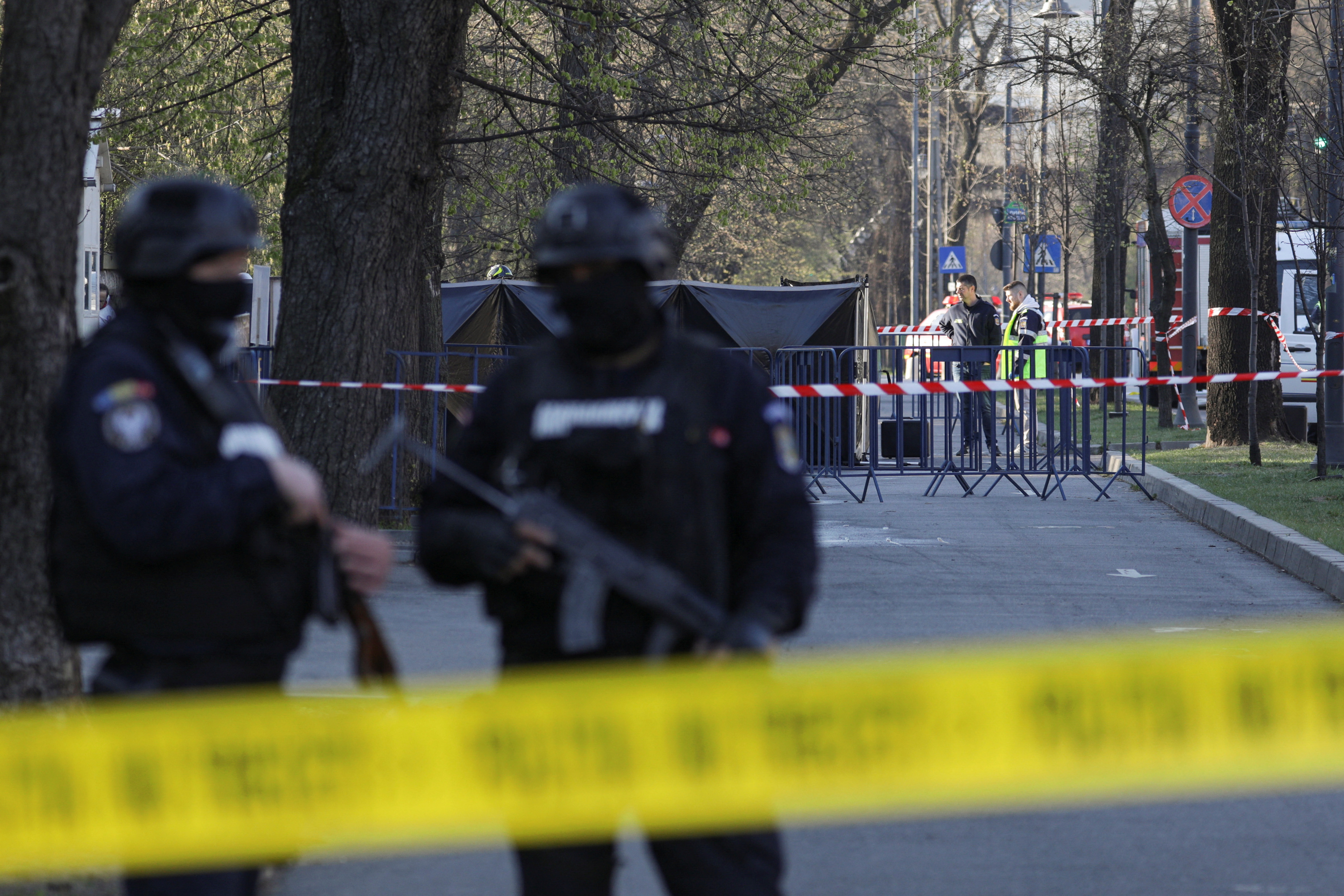 Police officers stand guard as crime scene investigators check the area where a car crashed into the gate of the Russian Embassy in Bucharest, Romania, on April 6.