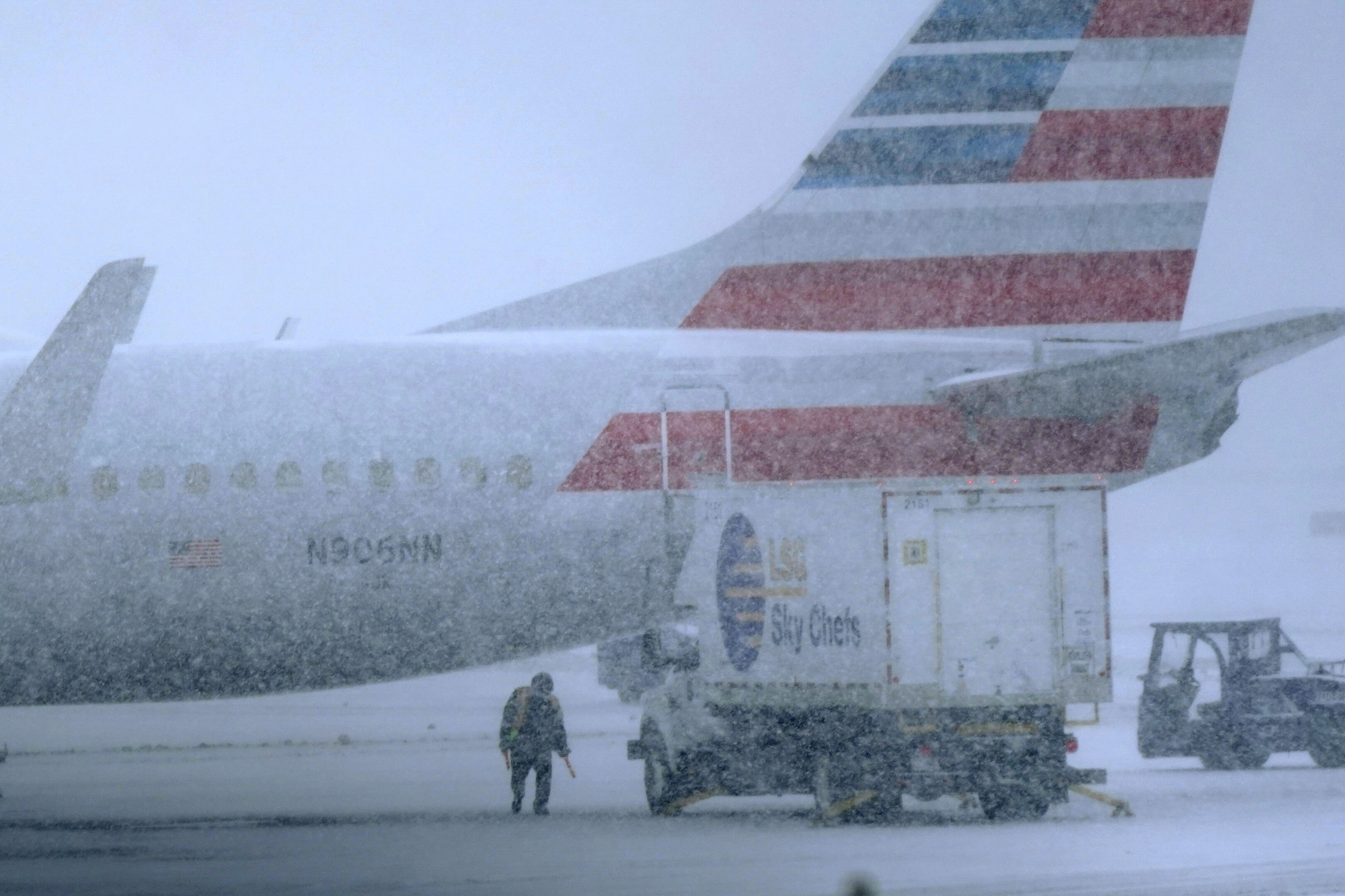 Snow falls on a ground crew working outside a parked plane at Dallas Fort Worth International Airport in Grapevine, Texas,  on Thursday.