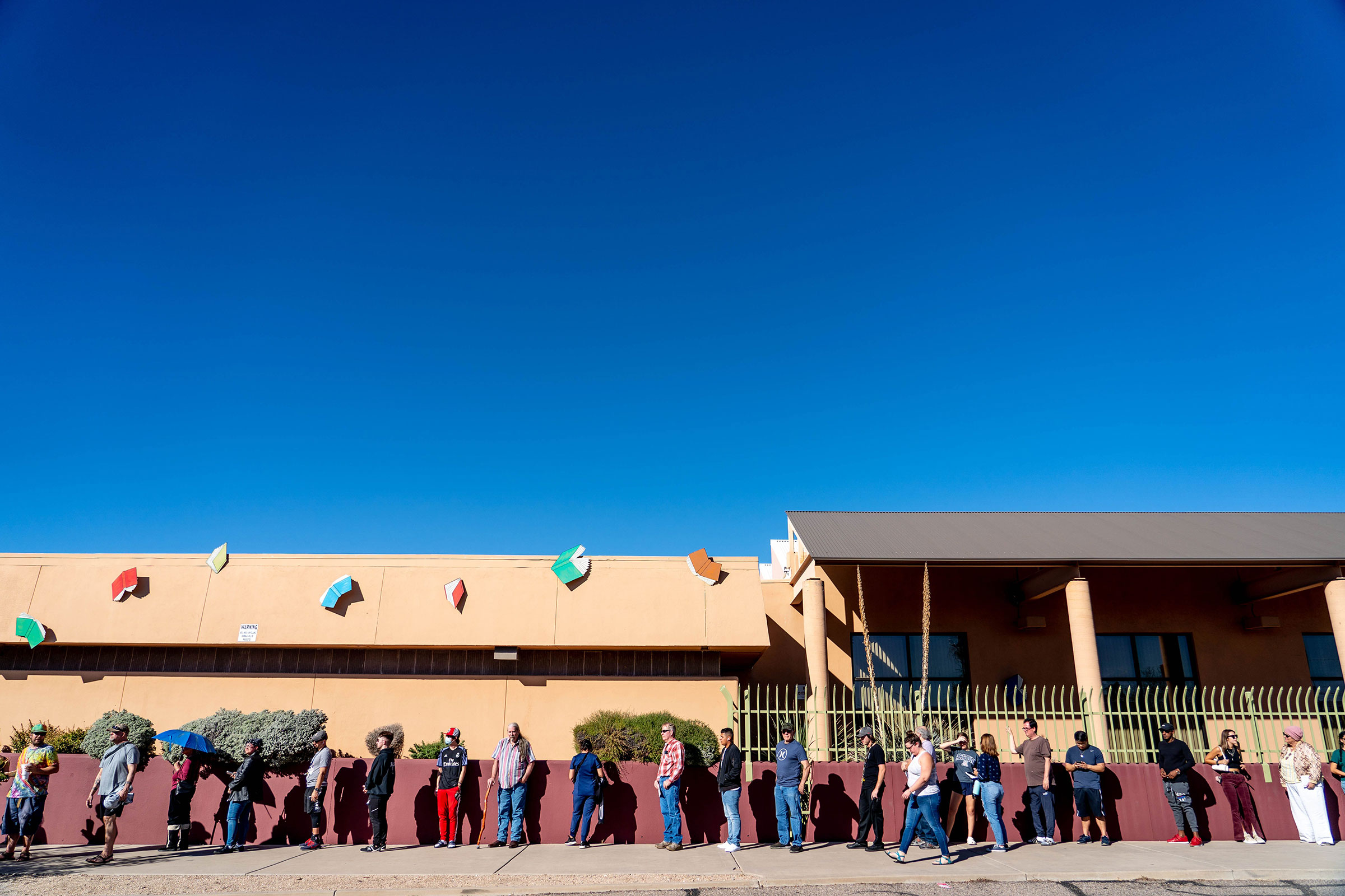 In this November 2022 photo, people wait in line to vote at a polling station at the Woods Memorial Library in Tucson, Arizona. 