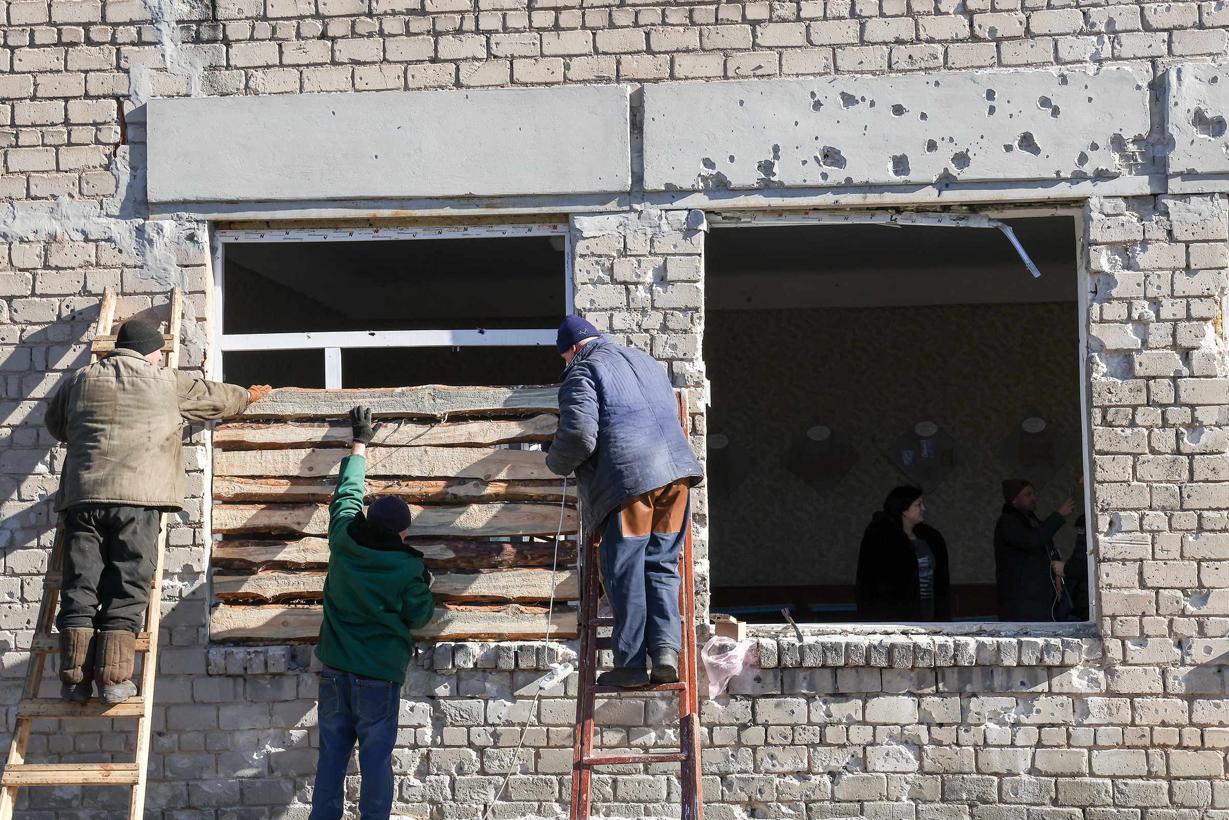 People board up a window at a school damaged in a shelling attack, in Donetsk region, on February 21. 