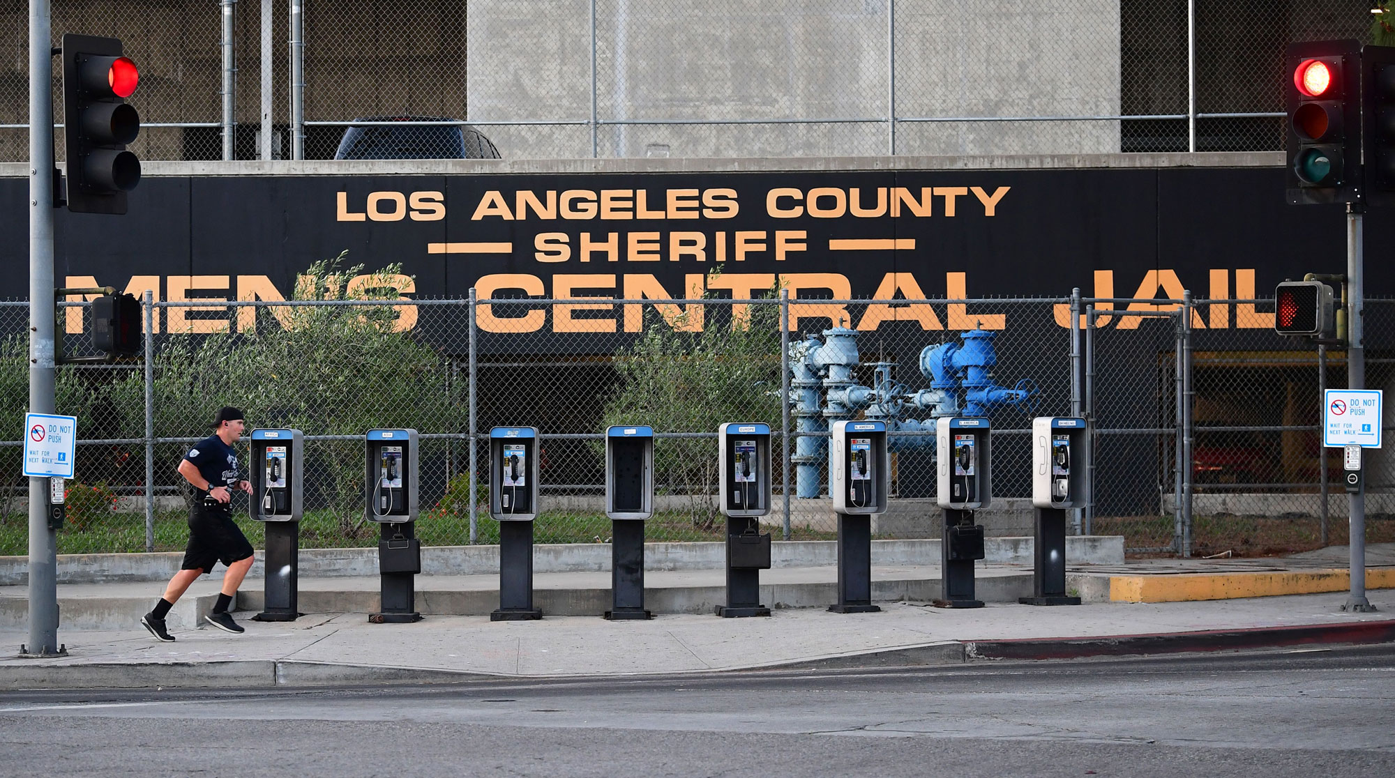 A man jogs past a row of telephone booths in front of the LA County Men's Central Jail on May 11 in Los Angeles. More than 5,000 inmates have been released from county jails in an effort to slow the spread of the coronavirus.