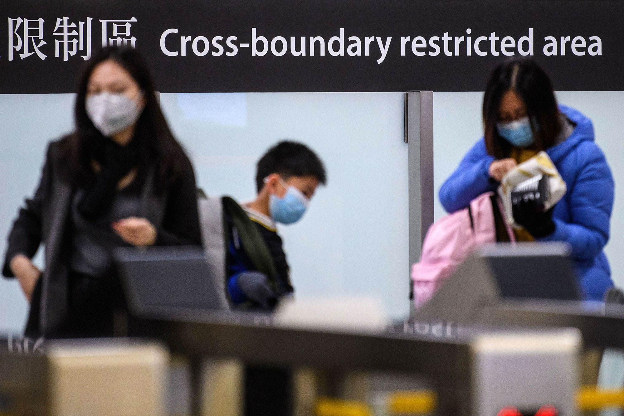 Commuters arriving in Hong Kong wear facemasks as they pass the cross boundary restricted area inside the high-speed train station connecting Hong Kong to mainland China.