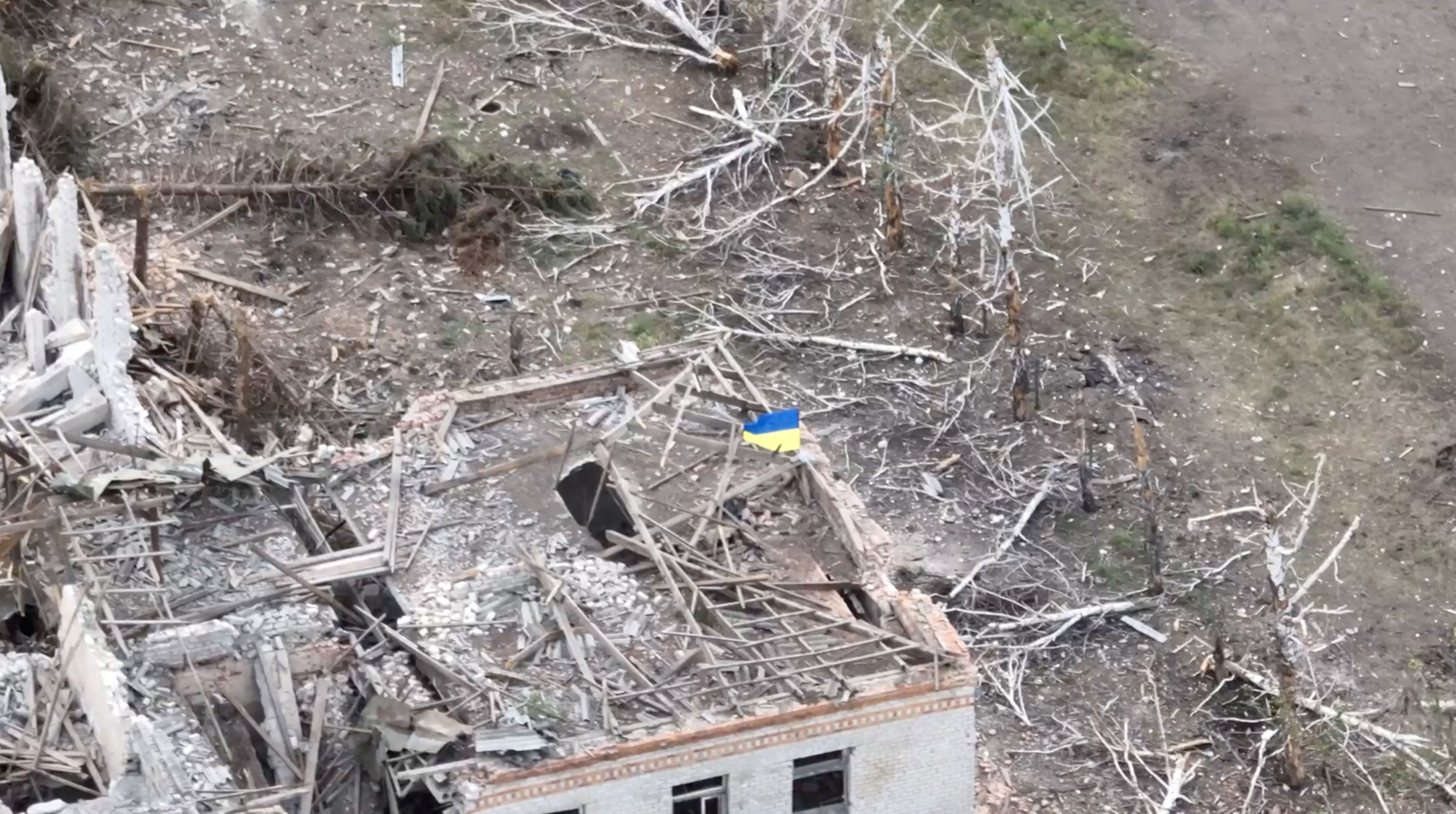 A Ukrainian flag flies above a destroyed building in the settlement of Robotyne, Ukraine, in this screen grab taken from a social media video released August 23.