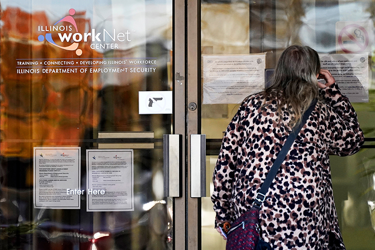 A woman checks information as information signs are displayed at IDES (Illinois Department of Employment Security) WorkNet center in Arlington Heights, Ill., Thursday, Nov. 5, 2020. 
