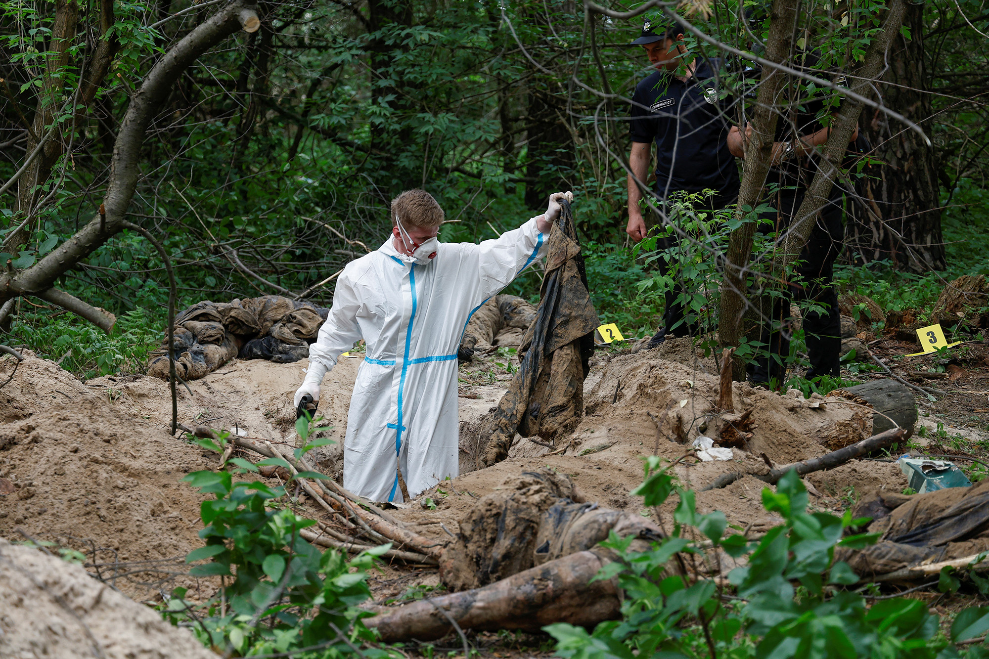 A forensic technician inspects an alleged mass grave near the village of Vorzel in the Bucha district, Kyiv region, Ukraine, on June 13.
