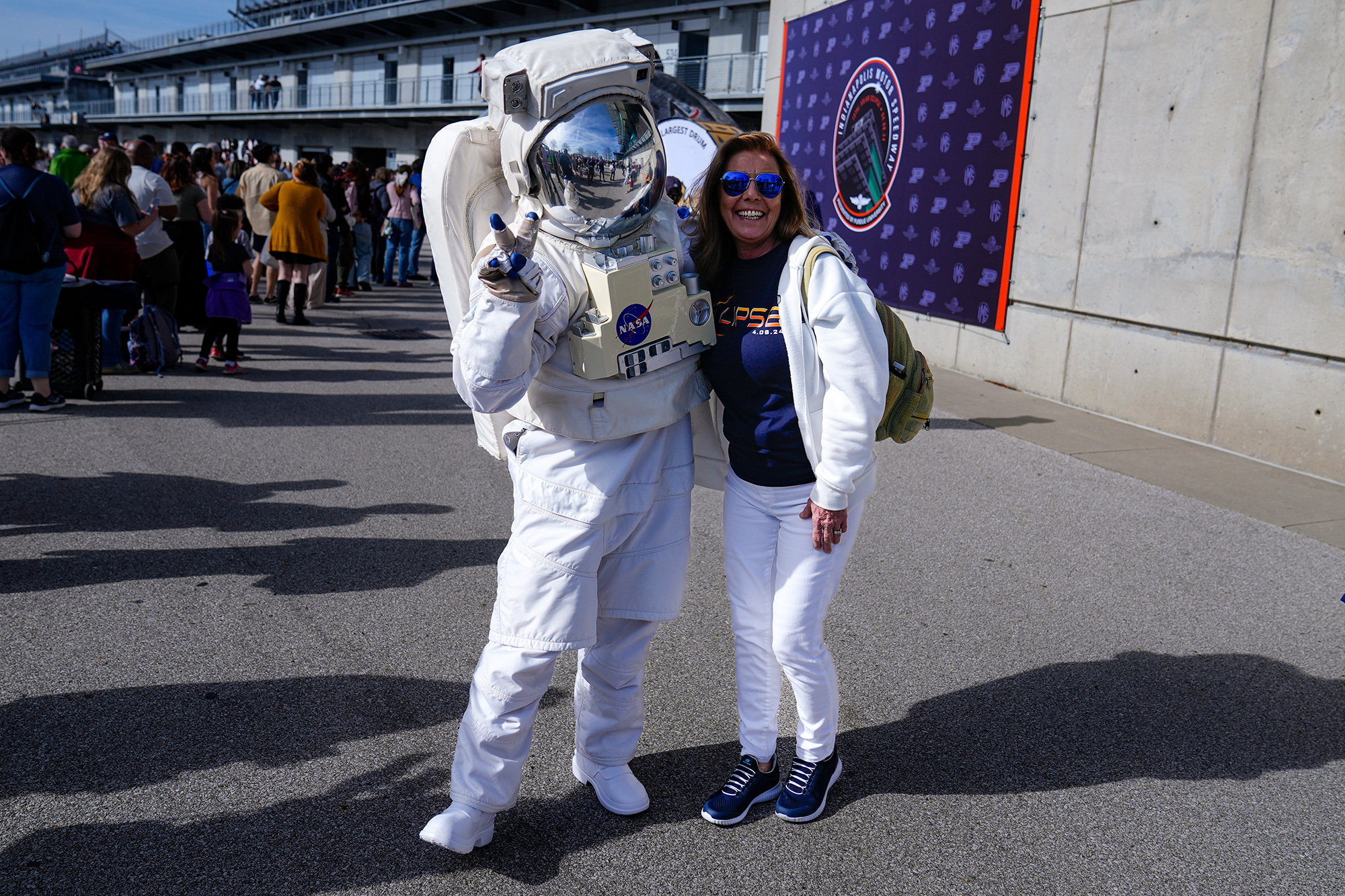 Tamra Sylvester poses with a person dressed as an astronaut during a eclipse viewing event at the Indianapolis Motor Speedway.