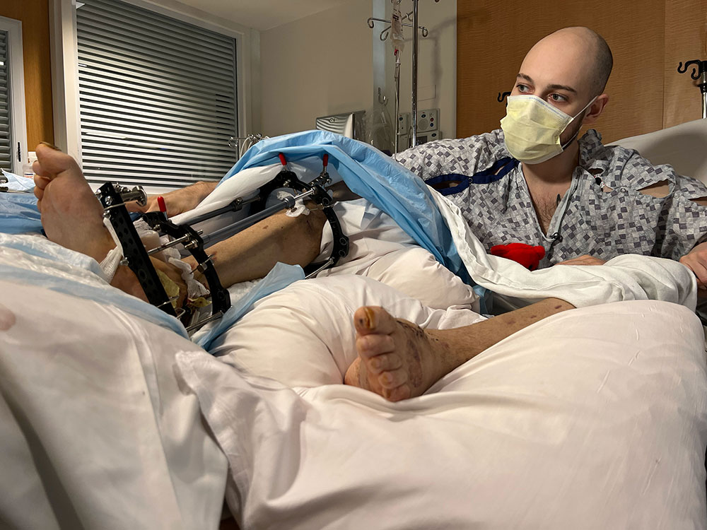 Vladyslav Orlov sits in his hospital bed after two major reconstructive surgeries.