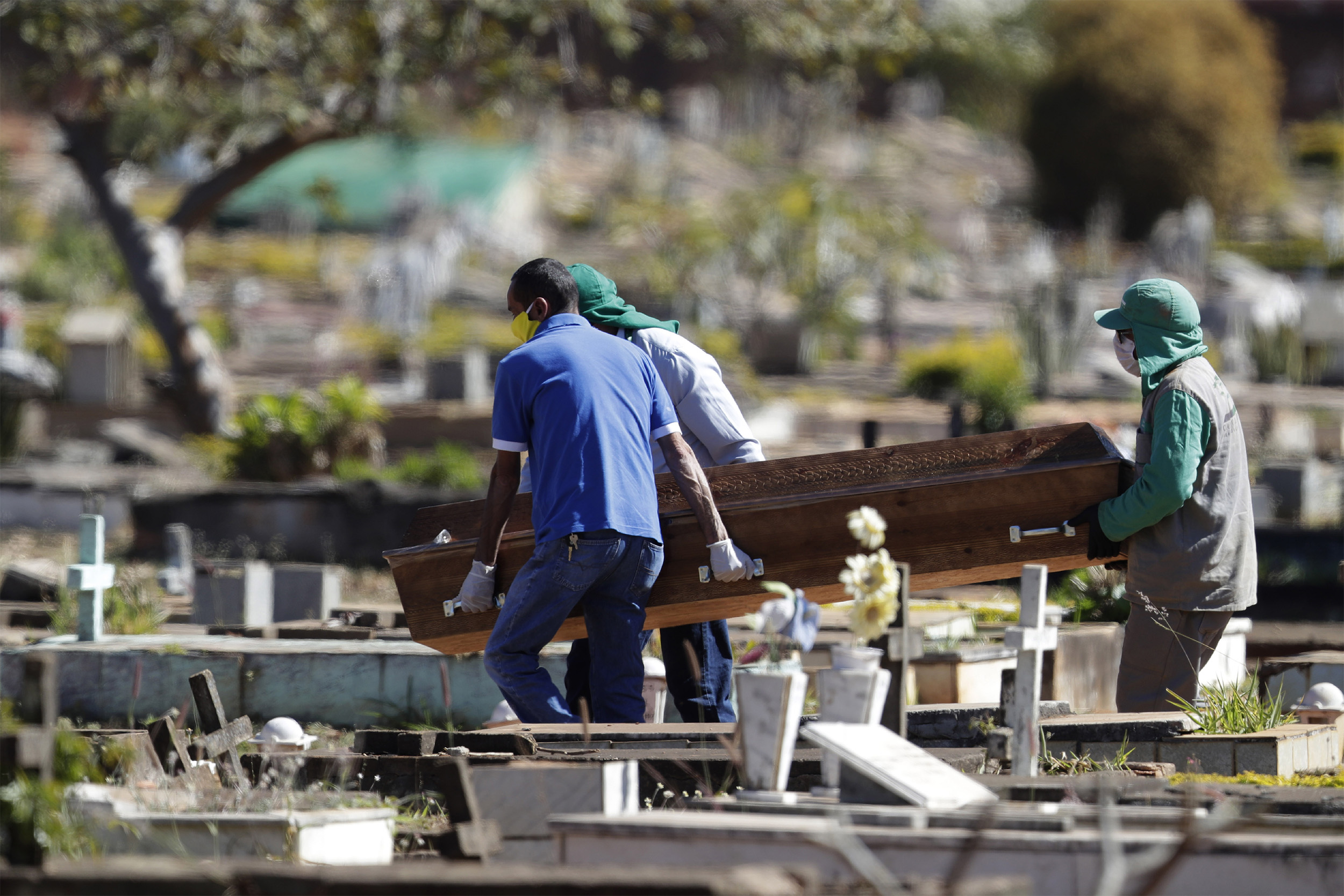 Cemetery workers carry the coffin of Bruno Correia, whose family said he died of COVID-19, to his gravesite at the Campo da Esperanca cemetery in Brasilia, Brazil, on Friday, July 17.