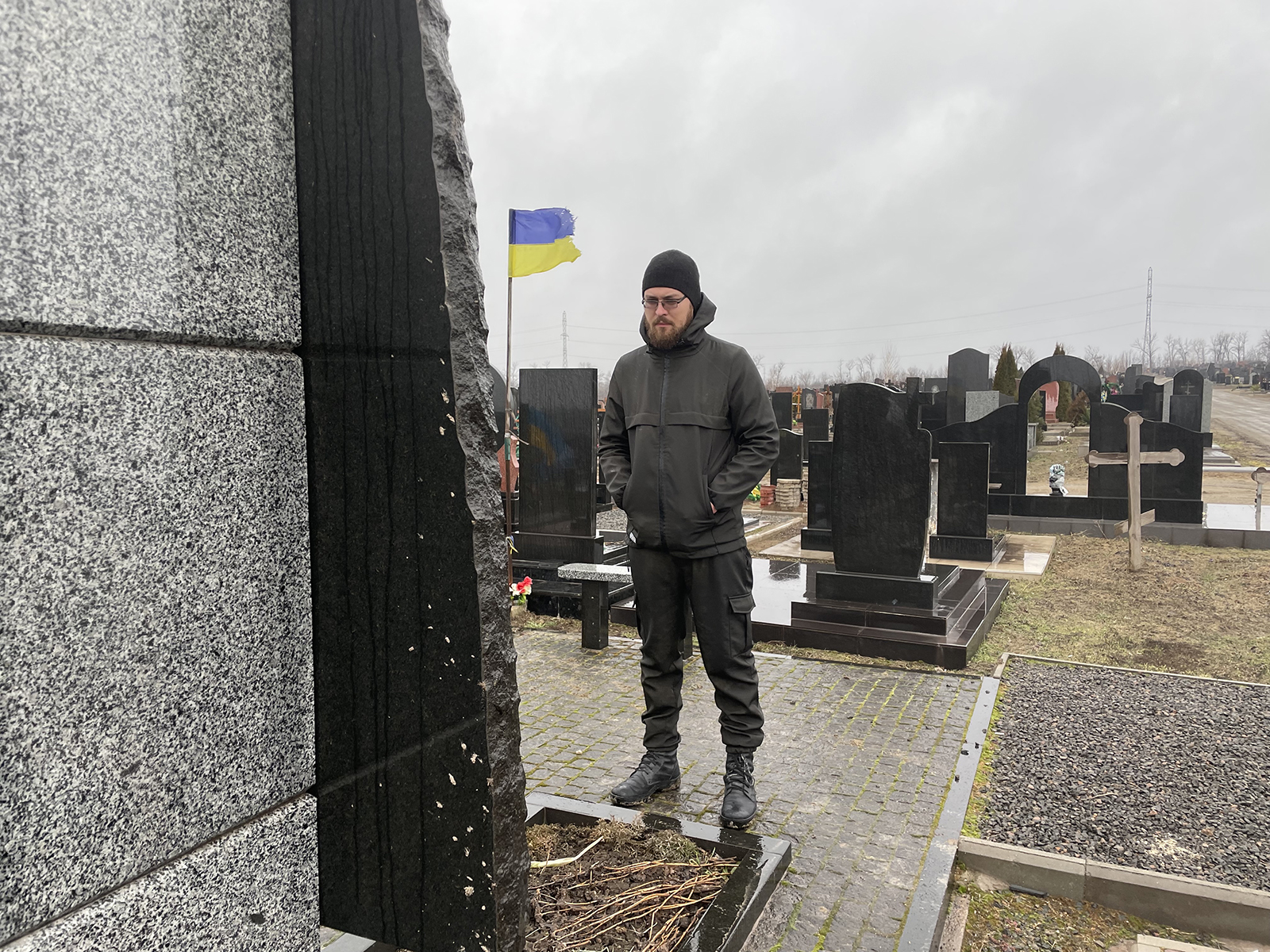 Roman Peretyatko stands over the grave of his friend whom he buried in 2015. As both a military and civilian chaplain, he makes both locals and soldiers feel at ease. 