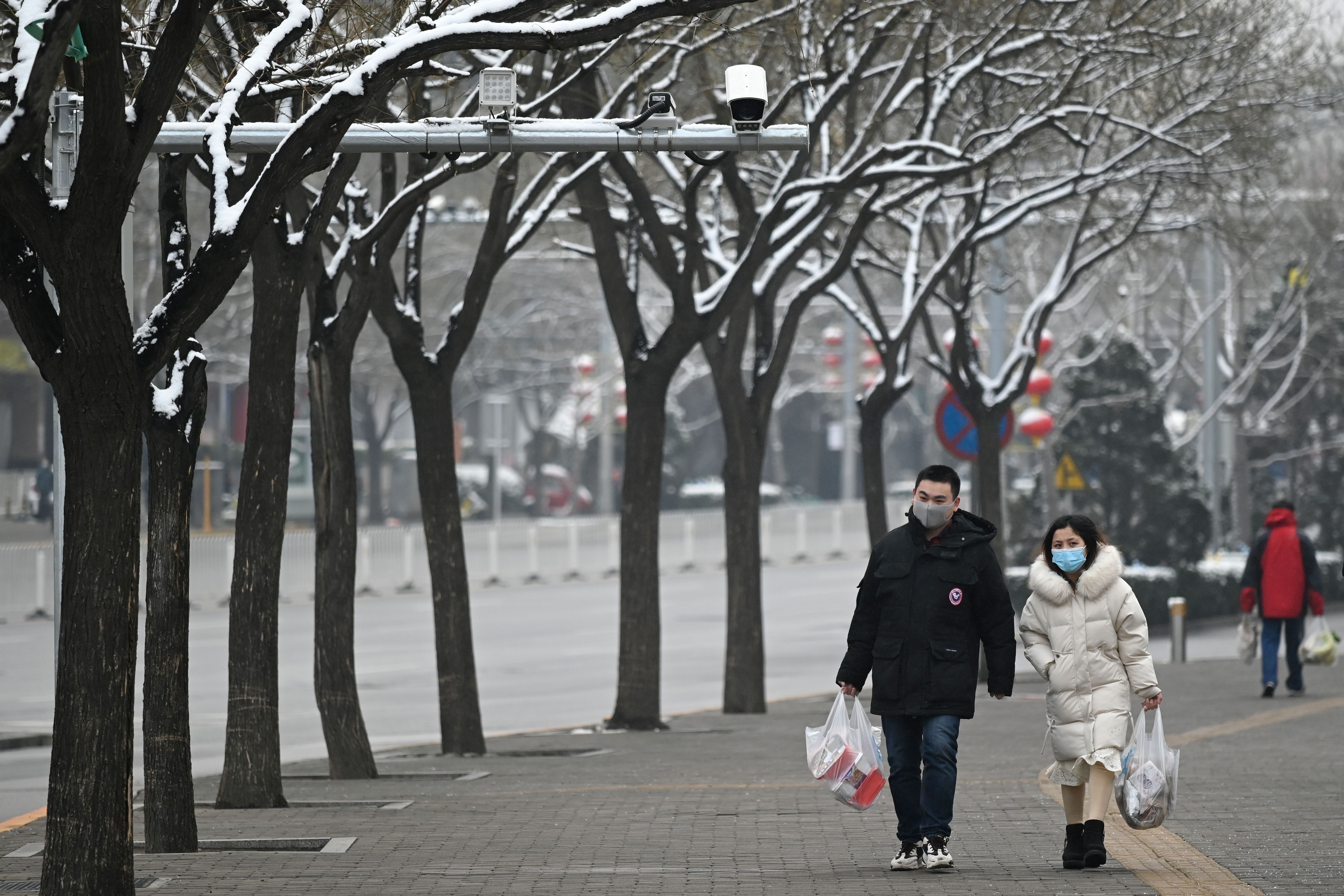 Pedestrians wearing masks walk along a road in Beijing on Sunday.