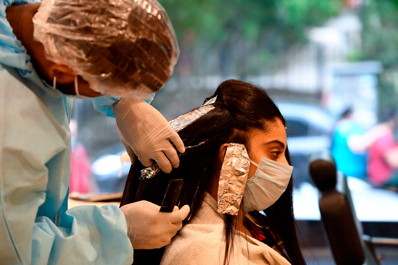 A hairdresser wearing personal protective equipment works on a customer at a hair salon in New Delhi on June 9.