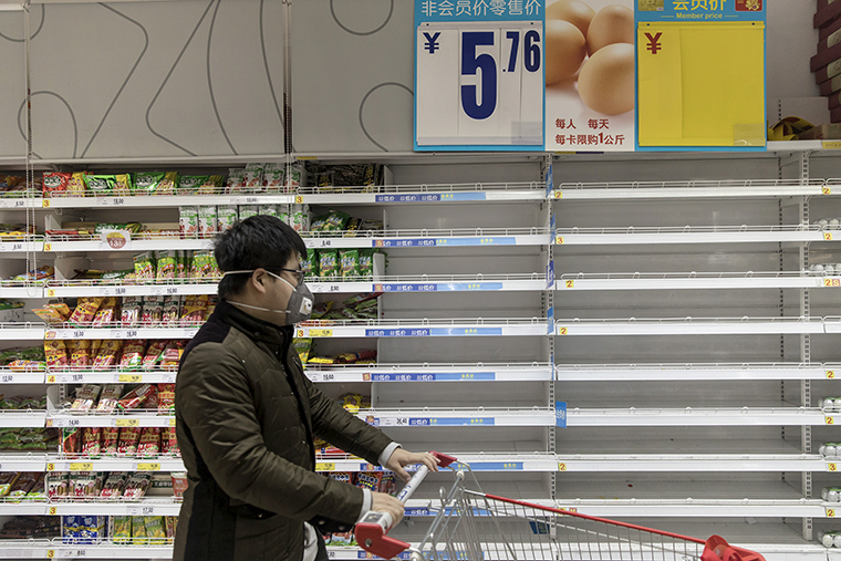 A customer pushes a cart past empty egg shelves at a supermarket in Shanghai, China, on Tuesday, January 28.