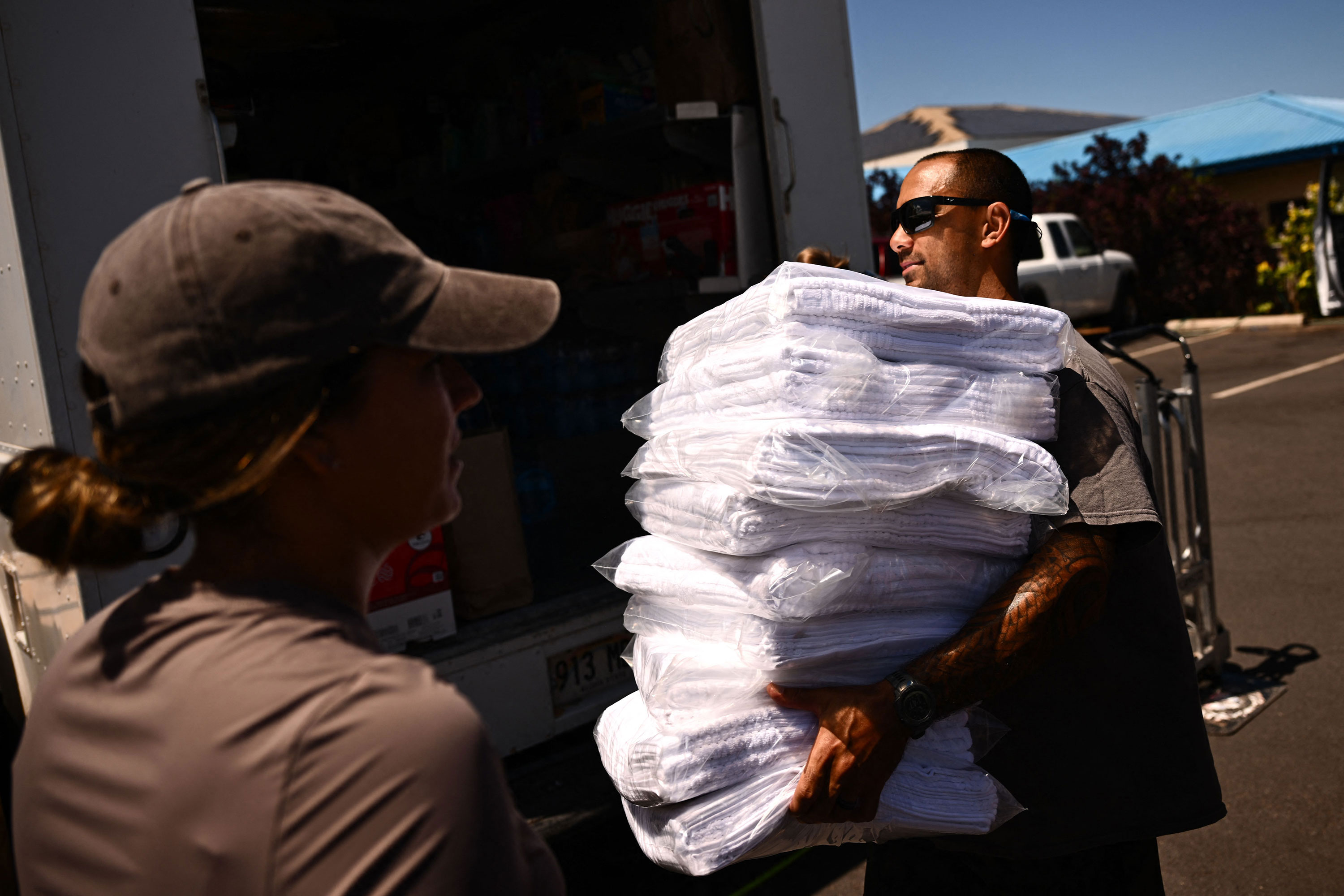 Volunteers carry donated supplies to distribute to fire victims in Wailuku, Hawaii, on Saturday. 