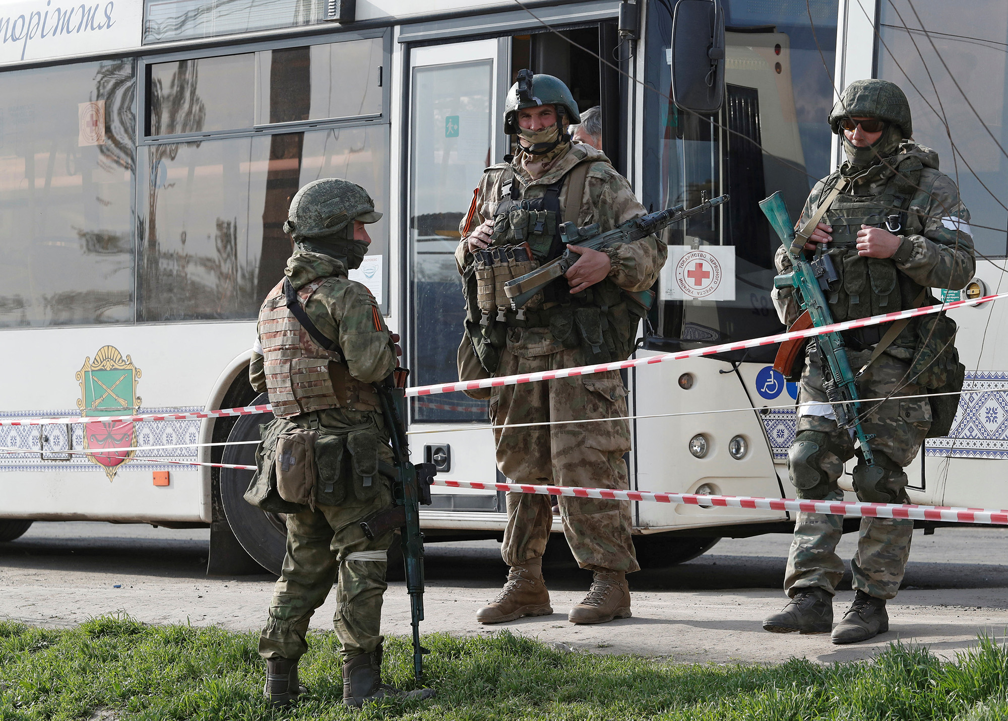 Pro-Russian troops stand guard next to a bus for transporting evacuees near a temporary accommodation center in the village of Bezimenne in the Donetsk Region, Ukraine, on May 1.