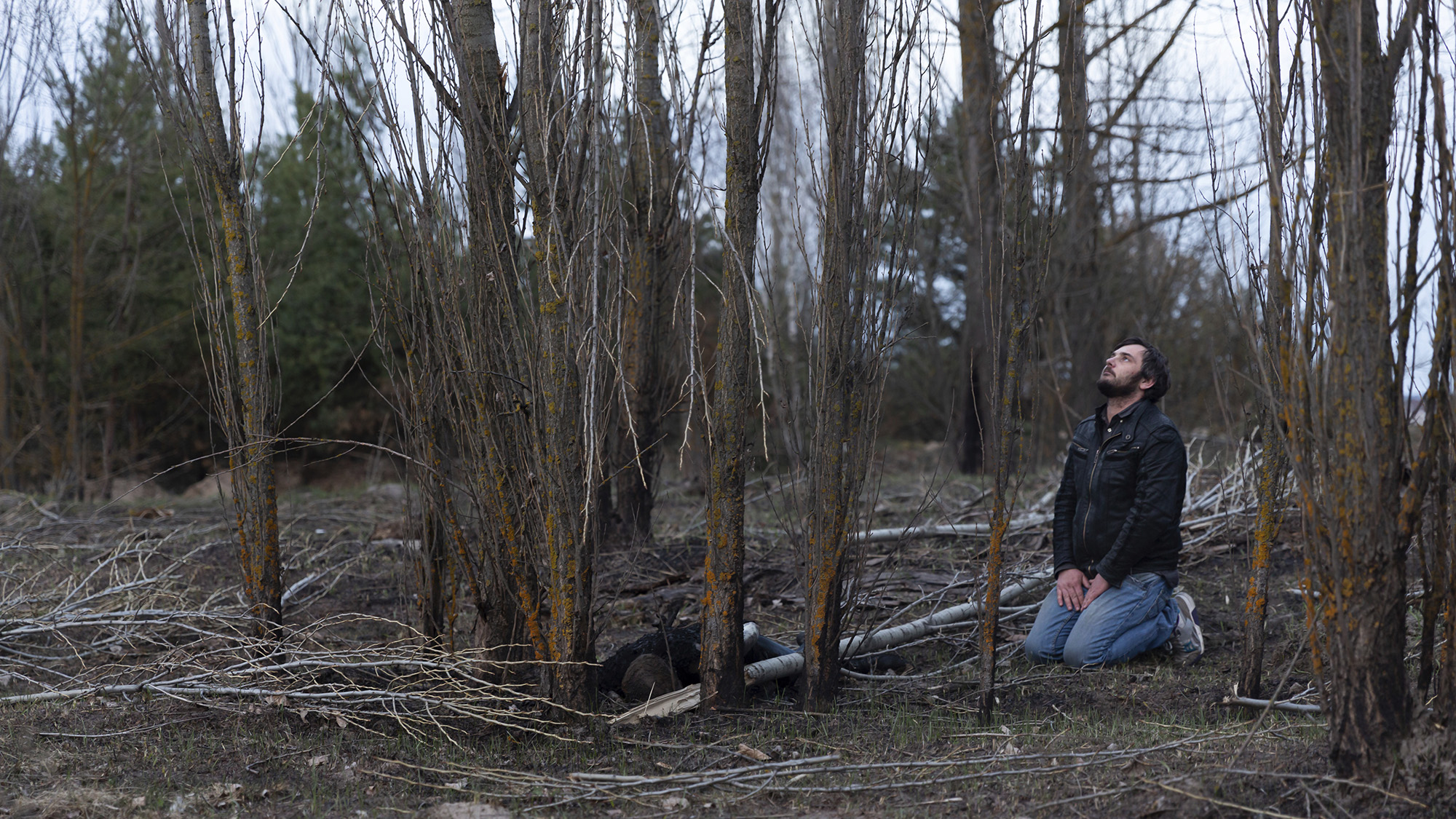 A Ukrainian man named Maxim prays next to a body of a male left at an abandoned Russian camp near Makariv, Ukraine on April 7.