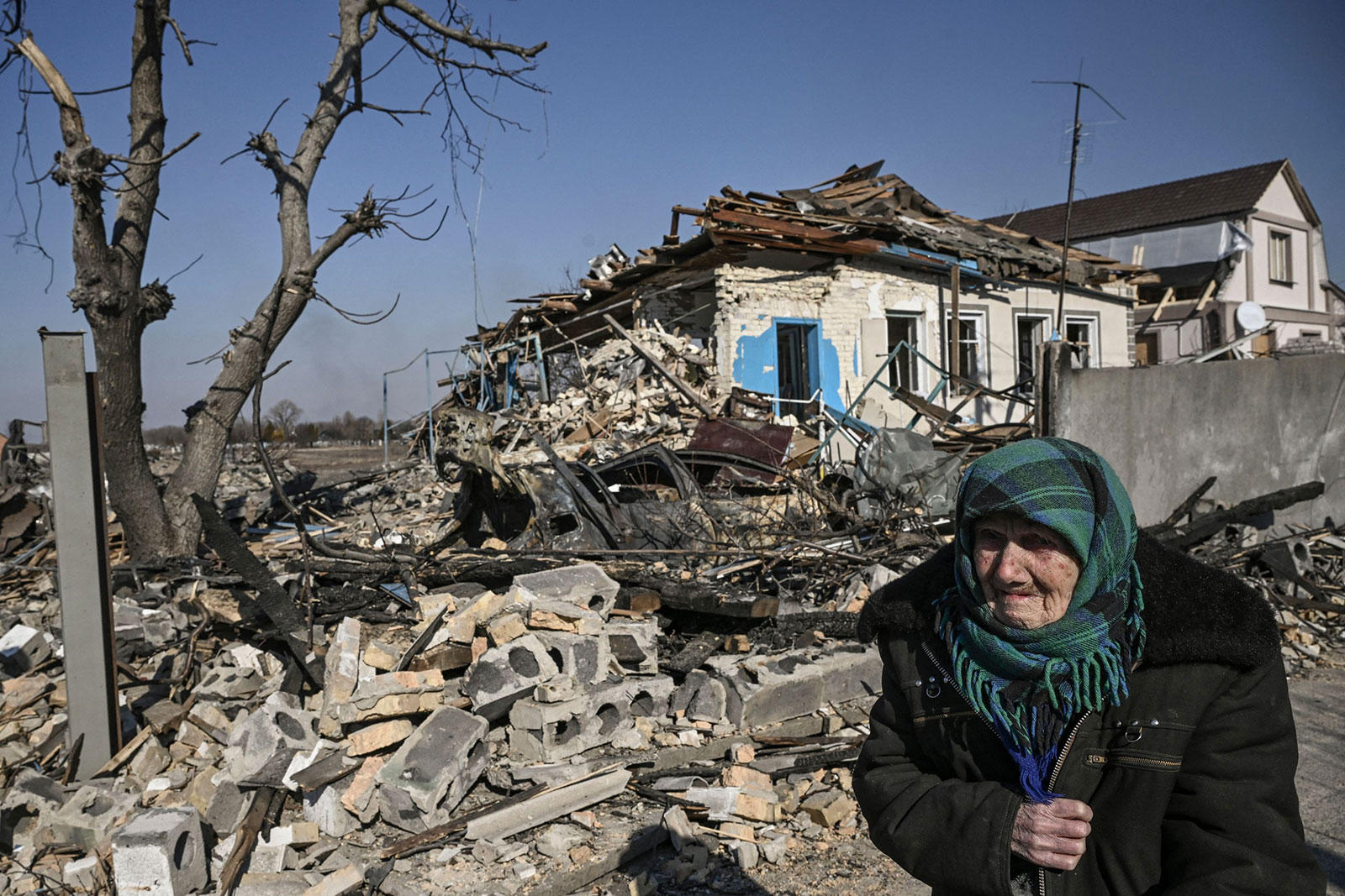 An elderly woman stands in front of a destroyed house after bombardments in the village of Krasylivka, east of Kyiv, on March 20. 