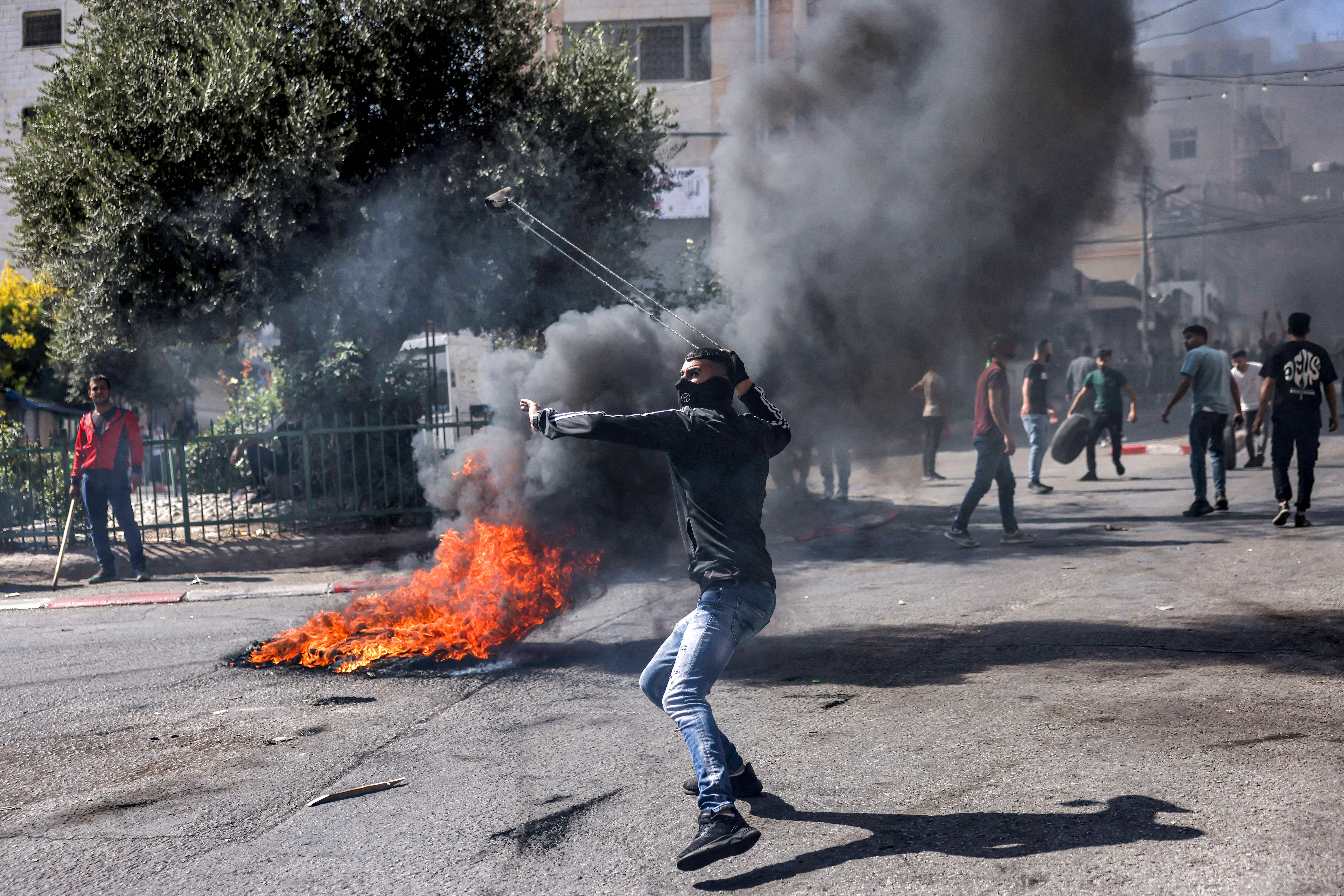 A Palestinian protester hurls back a tear gas canister with a sling during clashes with Israeli forces in the city of Hebron in the occupied West Bank on October 13.