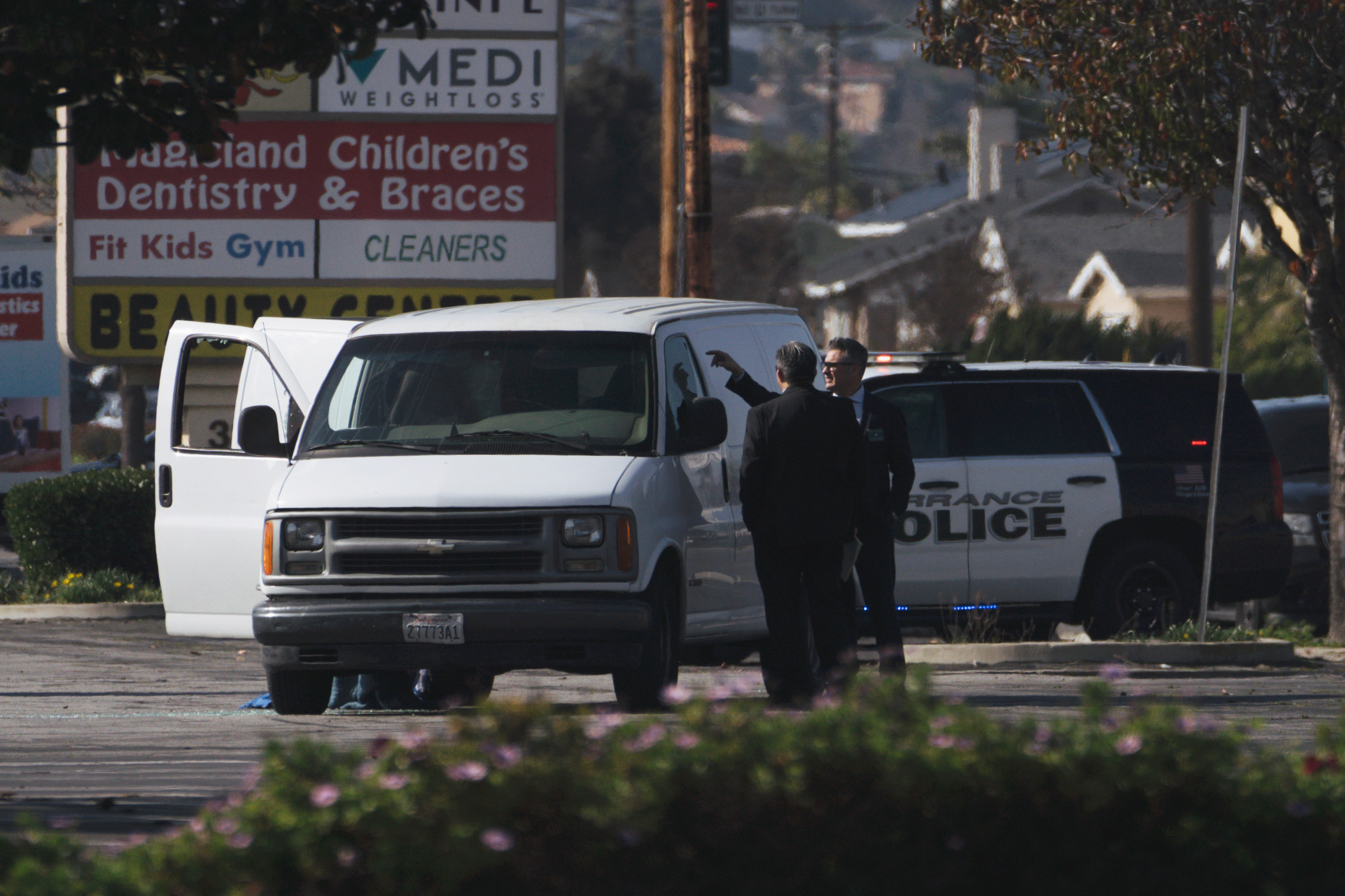 Law enforcement surrounds a white van in a parking lot that is being investigated for a possible connection to the earlier Monterey Park mass shooting in Torrance, California on Sunday.
