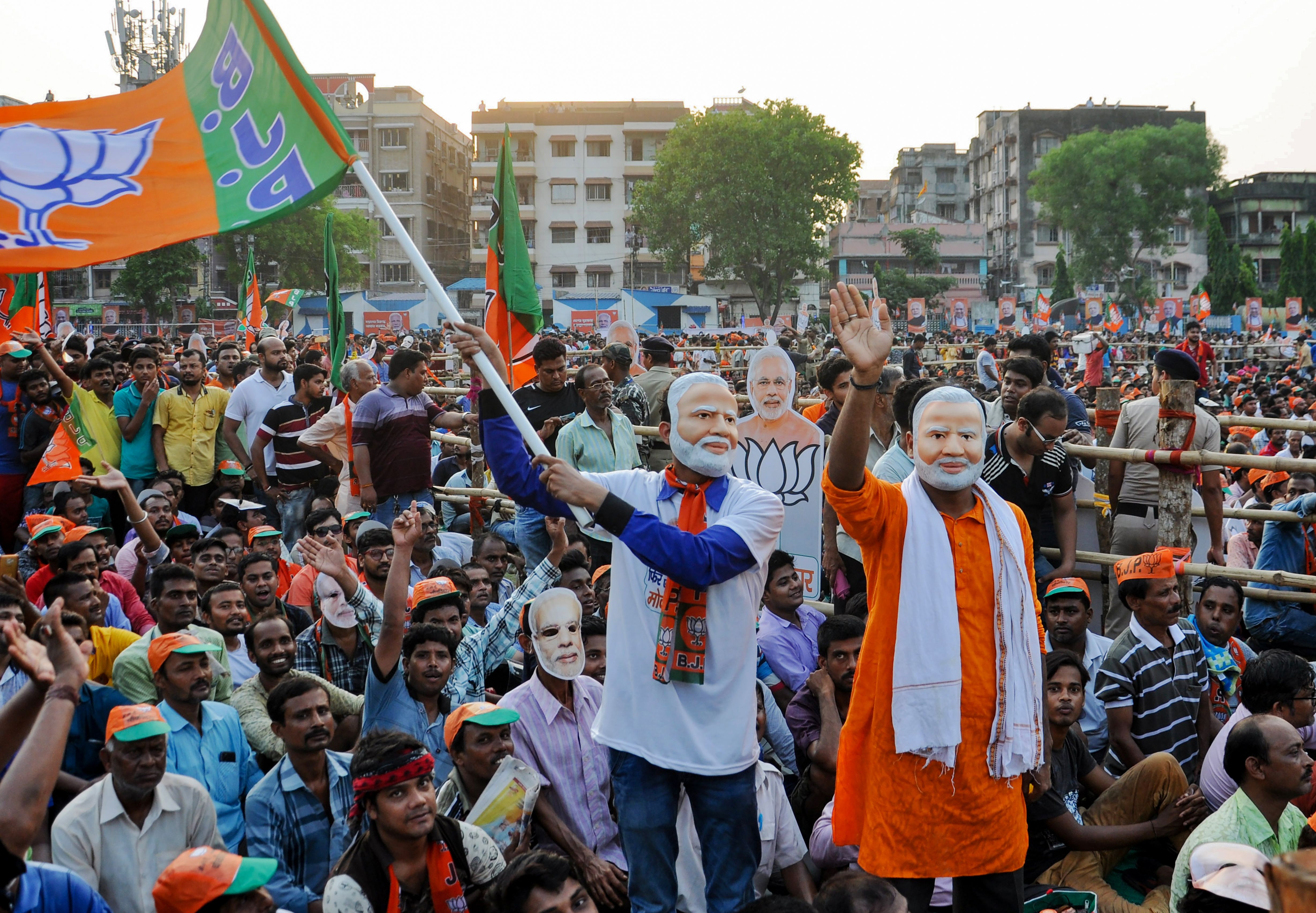 Supporters of the Bharatiya Janata Party (BJP) wave a party flag and wear masks of Prime Minister Narendra Modi in Kolkata on May 16, 2019. 