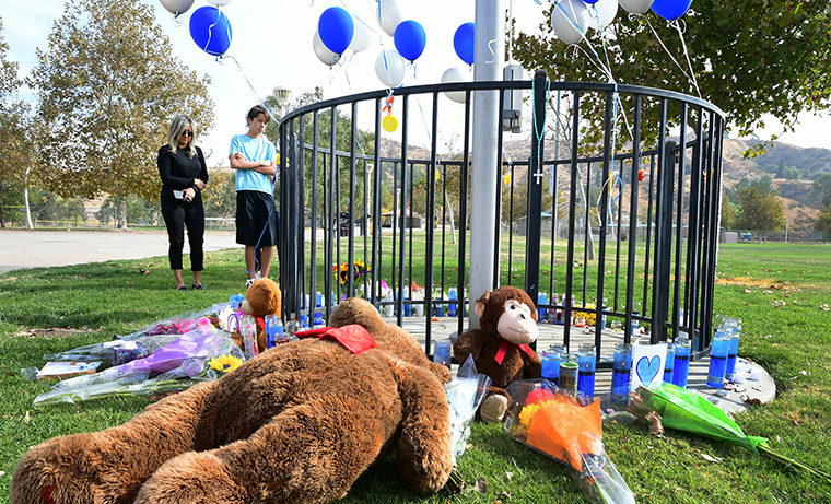 People grive beside a makeshift memorial in Central Park, not far from Saugus High School.