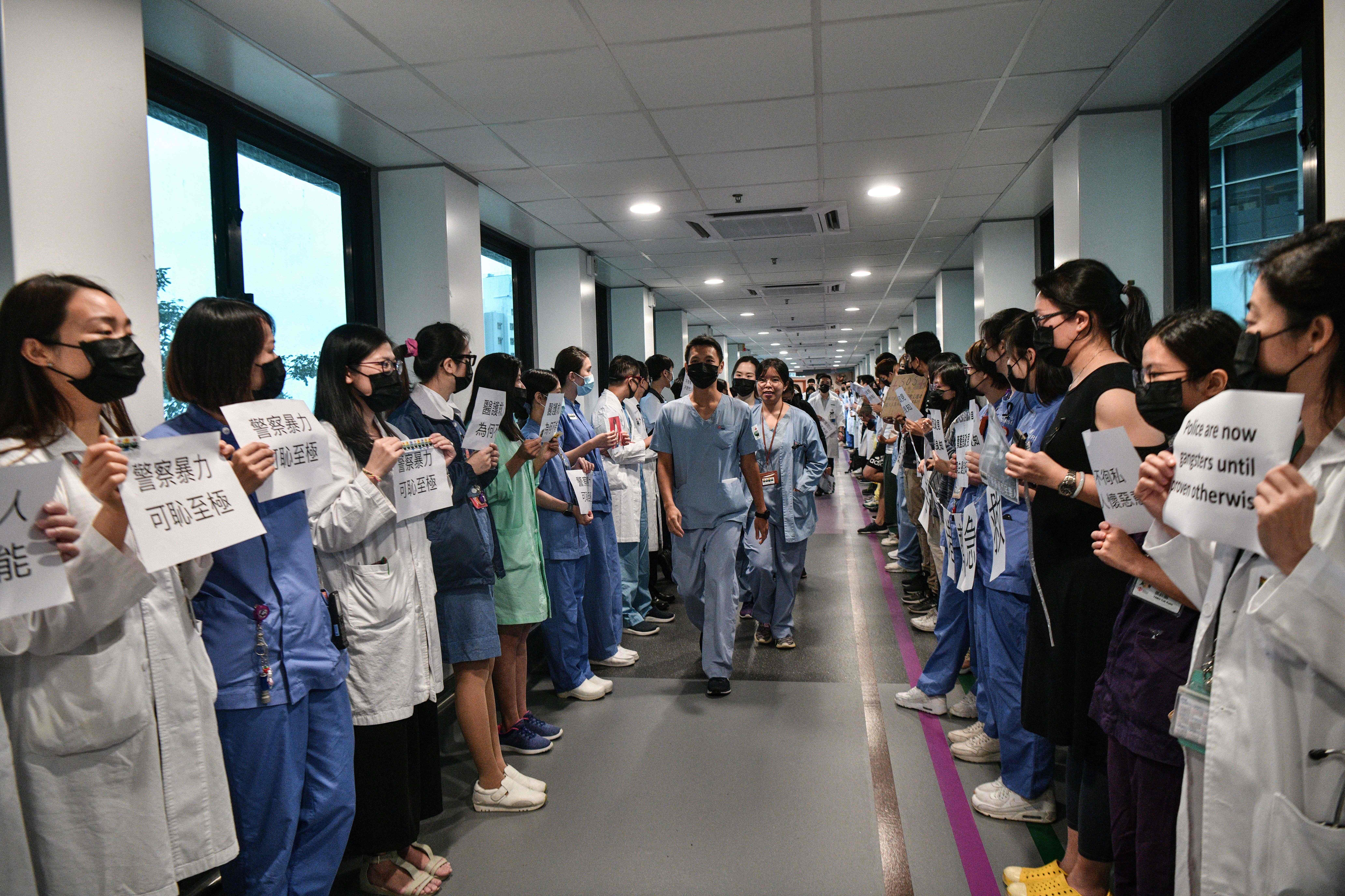 Medical staff hold posters as they form a human chain to express solidarity with anti-extradition bill protesters during their lunch break at the Queen Mary Hospital.