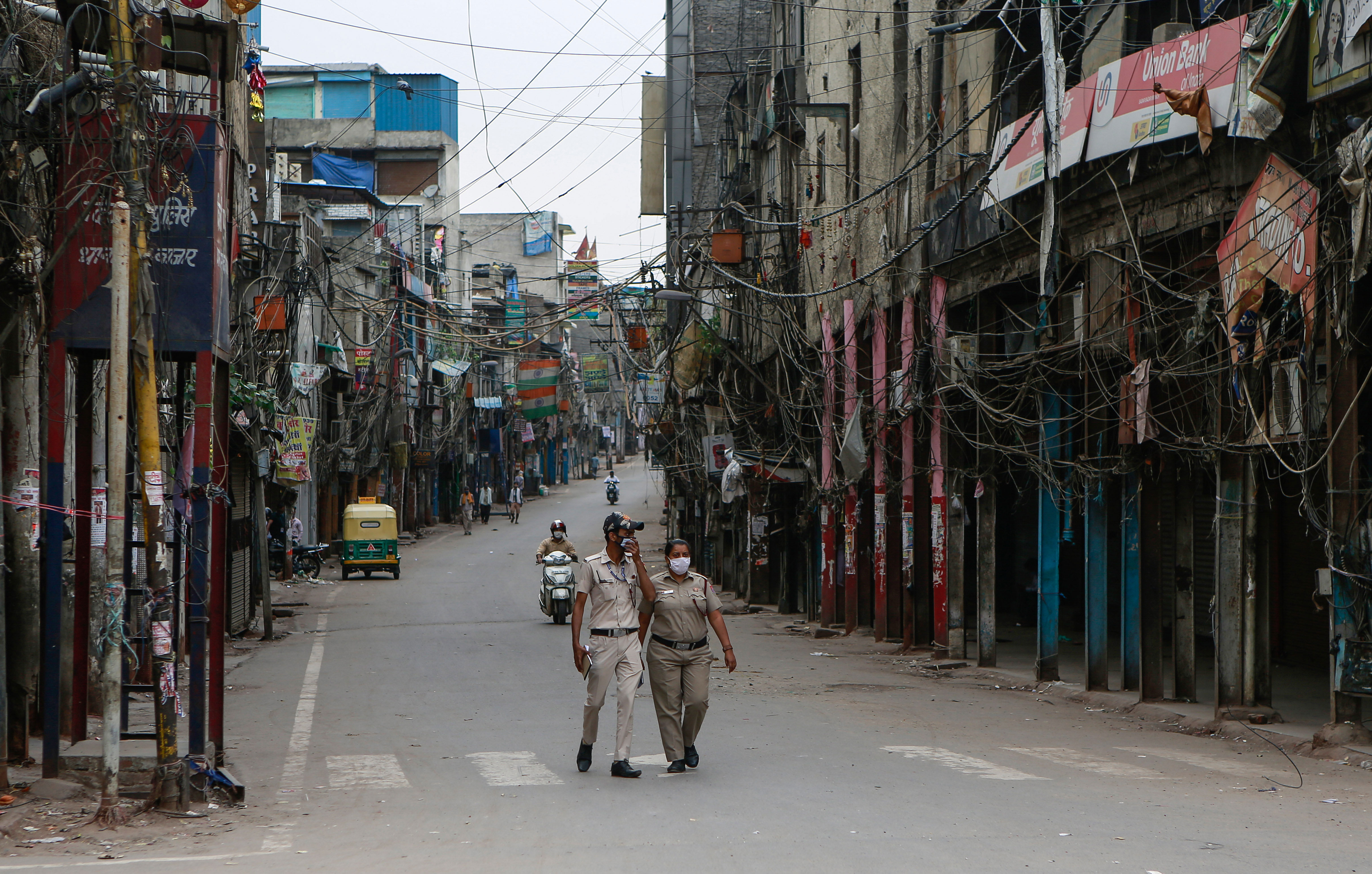 Police officers patrol a street with closed shops during a lockdown in New Delhi on April 20.