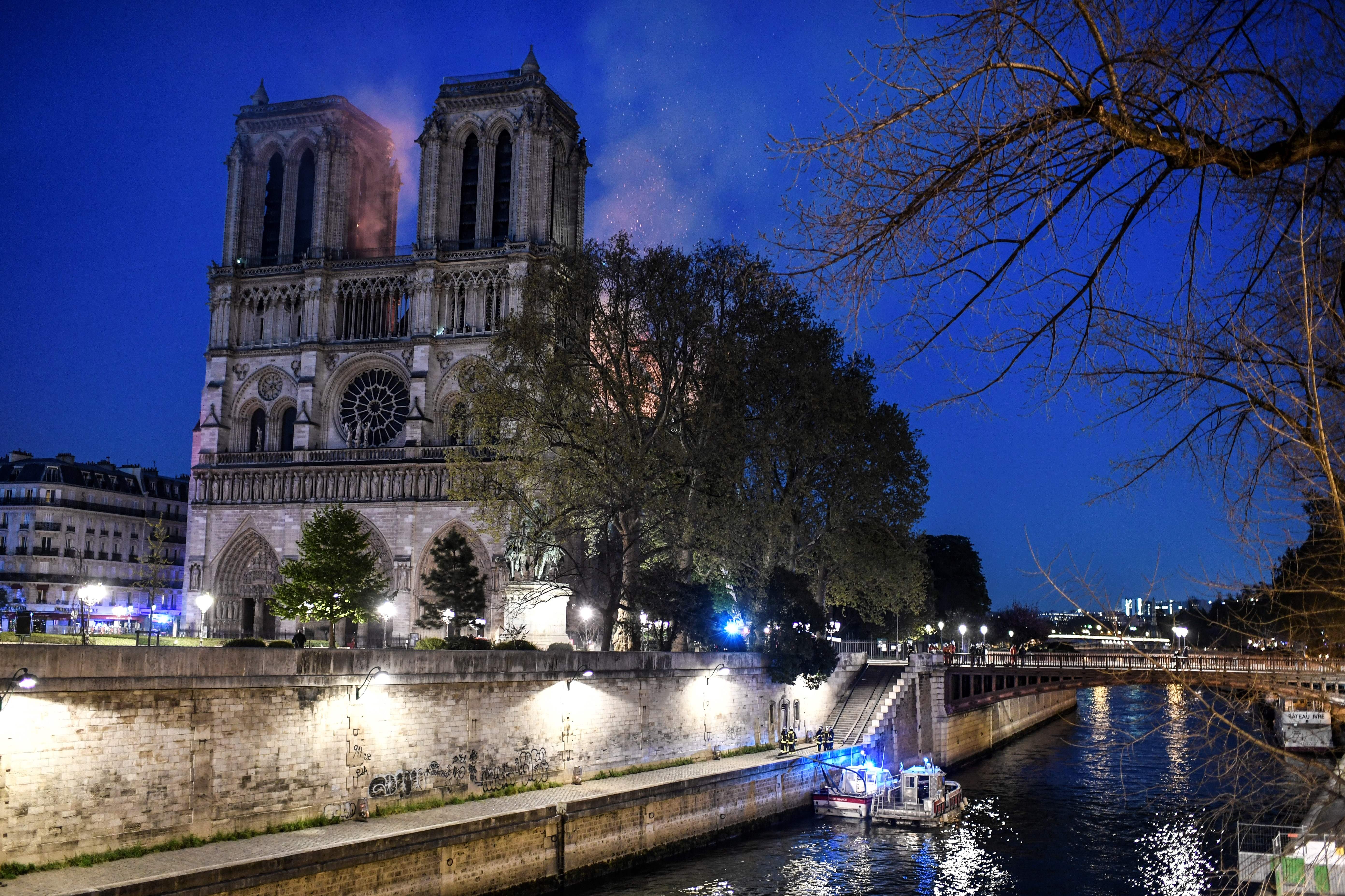 Firefighters work from a quay of the River Seine at the base of Notre Dame.