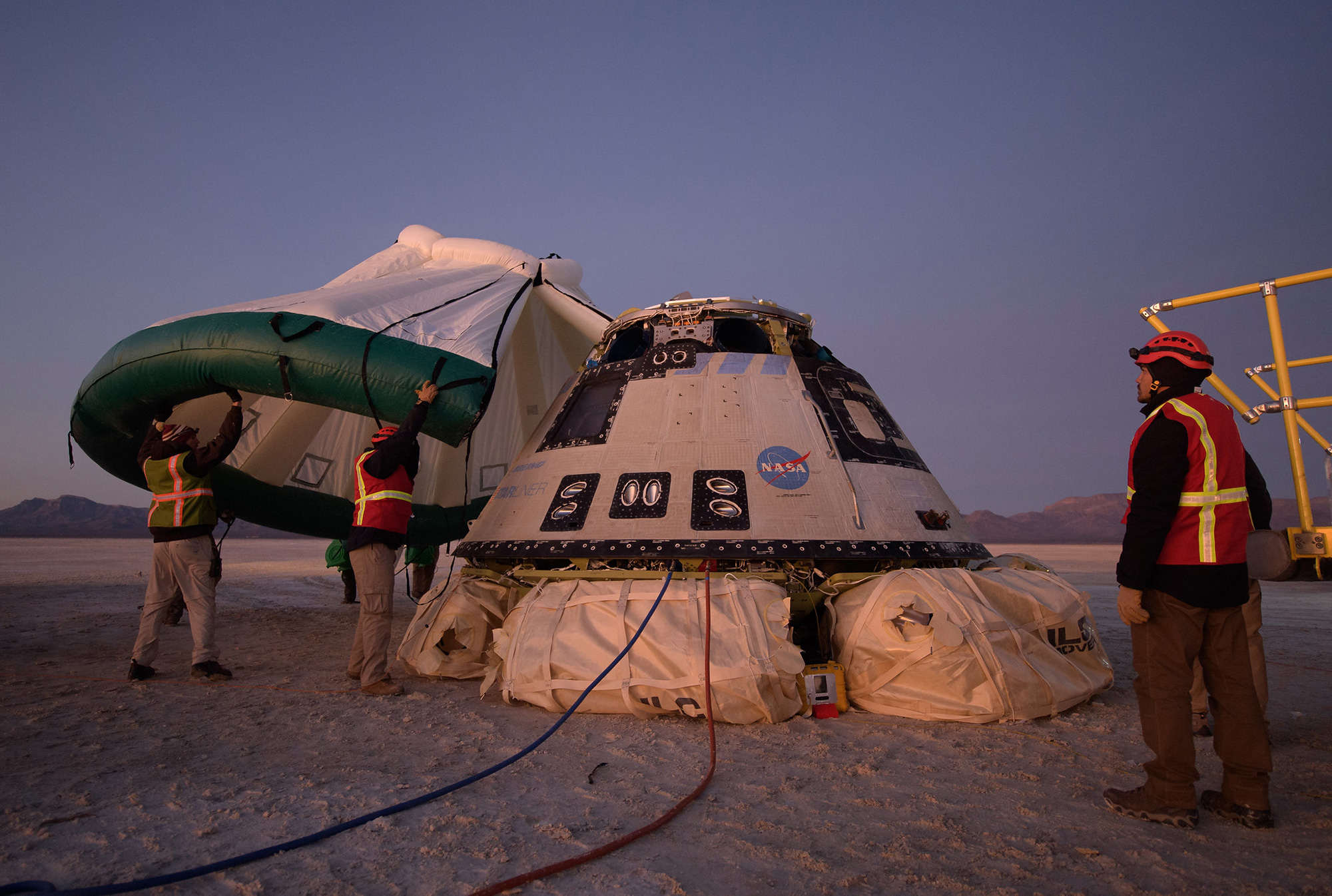 Mitarbeiter von Boeing, NASA und der US-Armee arbeiten rund um das Raumschiff Boeing CST-100 Starliner, kurz nachdem es im Dezember 2019 von einem Testflug in White Sands, New Mexico, gelandet ist. 