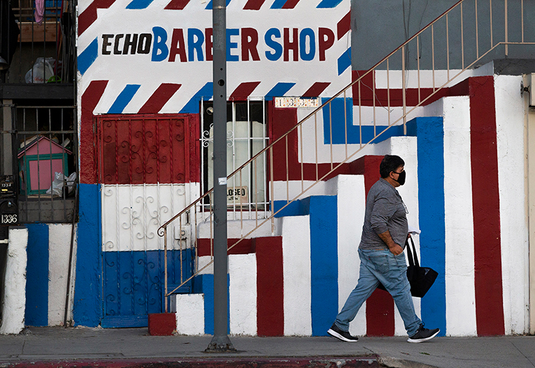 A pedestrian wears a mask as he walks past the closed Echo Barber Shop in the Echo Park neighborhood of Los Angeles, Friday, May 8. 
