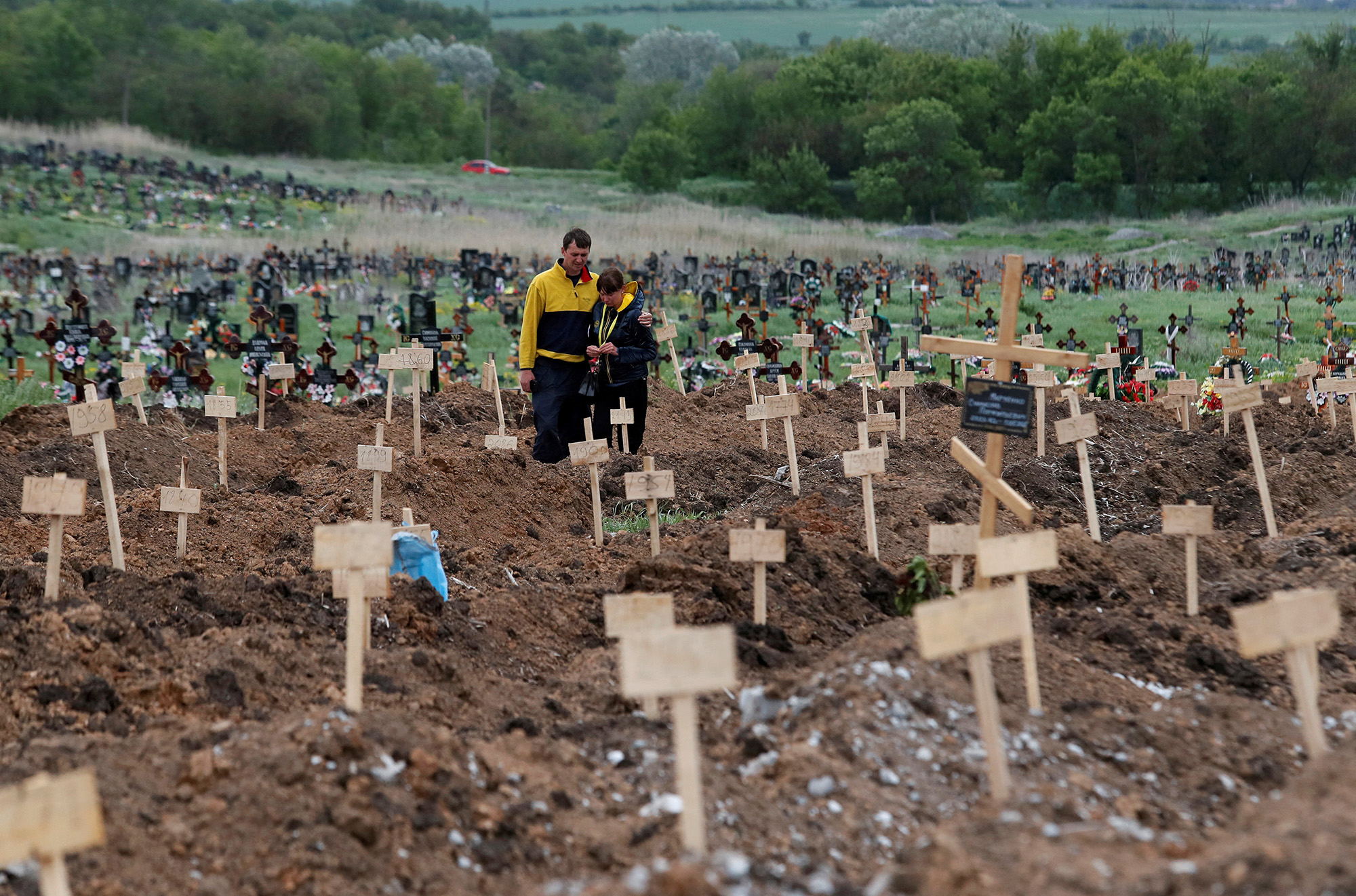 People stand amid newly-made graves at a cemetery outside Mariupol, Ukraine on May 22.