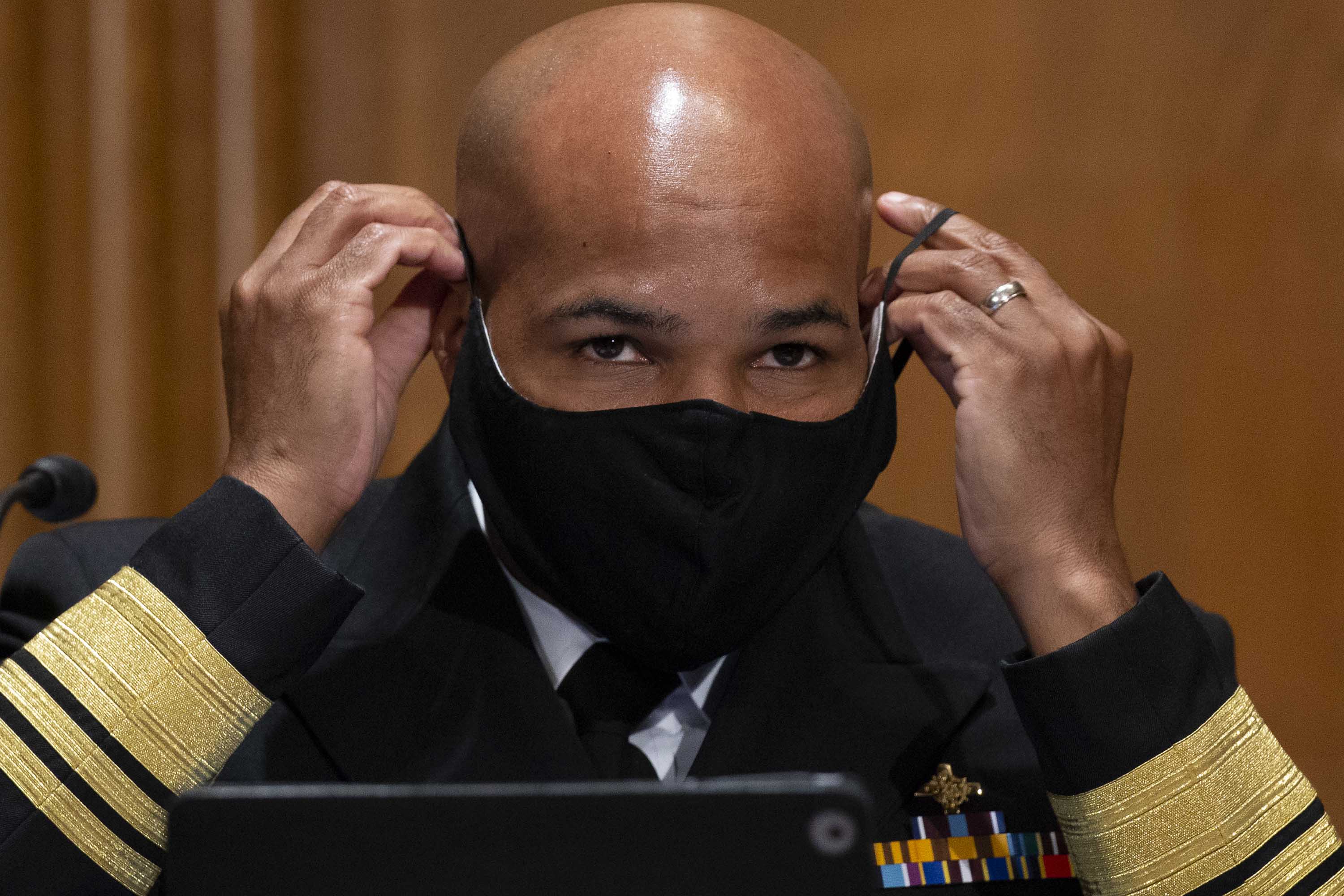 US Surgeon General Jerome Adams puts on a face mask during a Senate Health, Education, Labor, and Pensions Committee hearing to discuss vaccines and protecting public health during the coronavirus pandemic on September 9, in Washington DC.