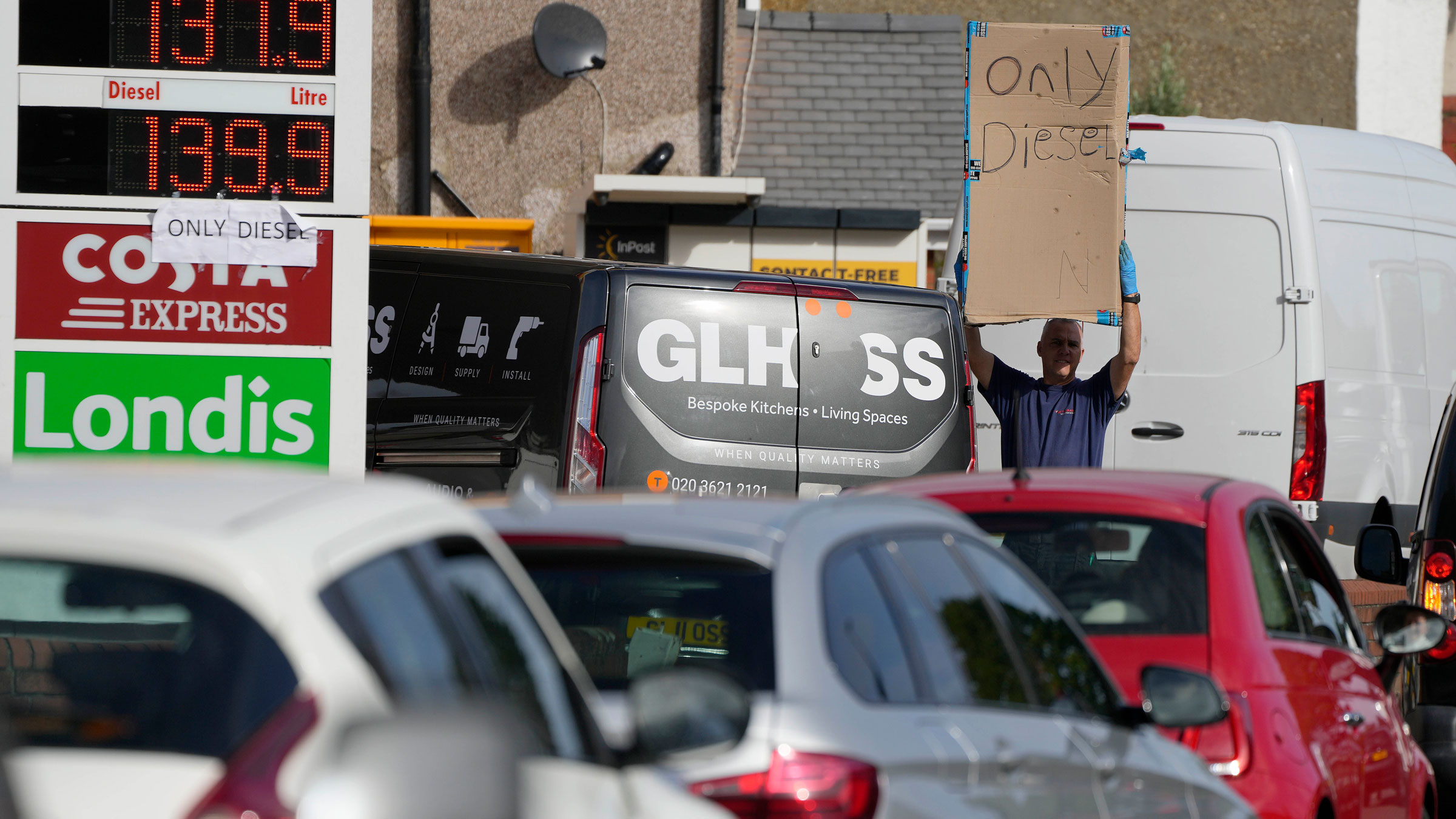 Drivers line up for fuel as a man holds a sign saying "only diesel" at a gas station in London on Tuesday.