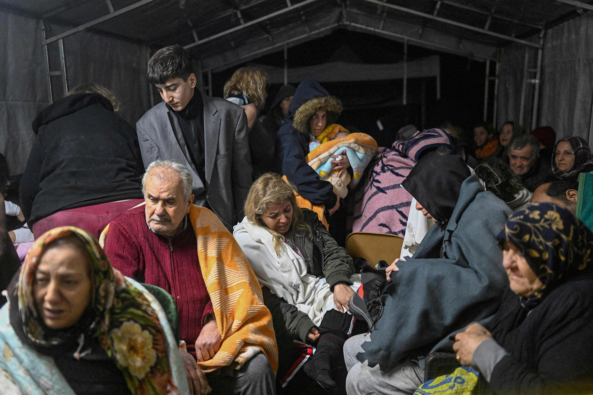 Earthquake survivors sit sheltering in a tent the day after a 7.8-magnitude earthquake struck the country's southeast in Hatay, Turkey, on February 7.