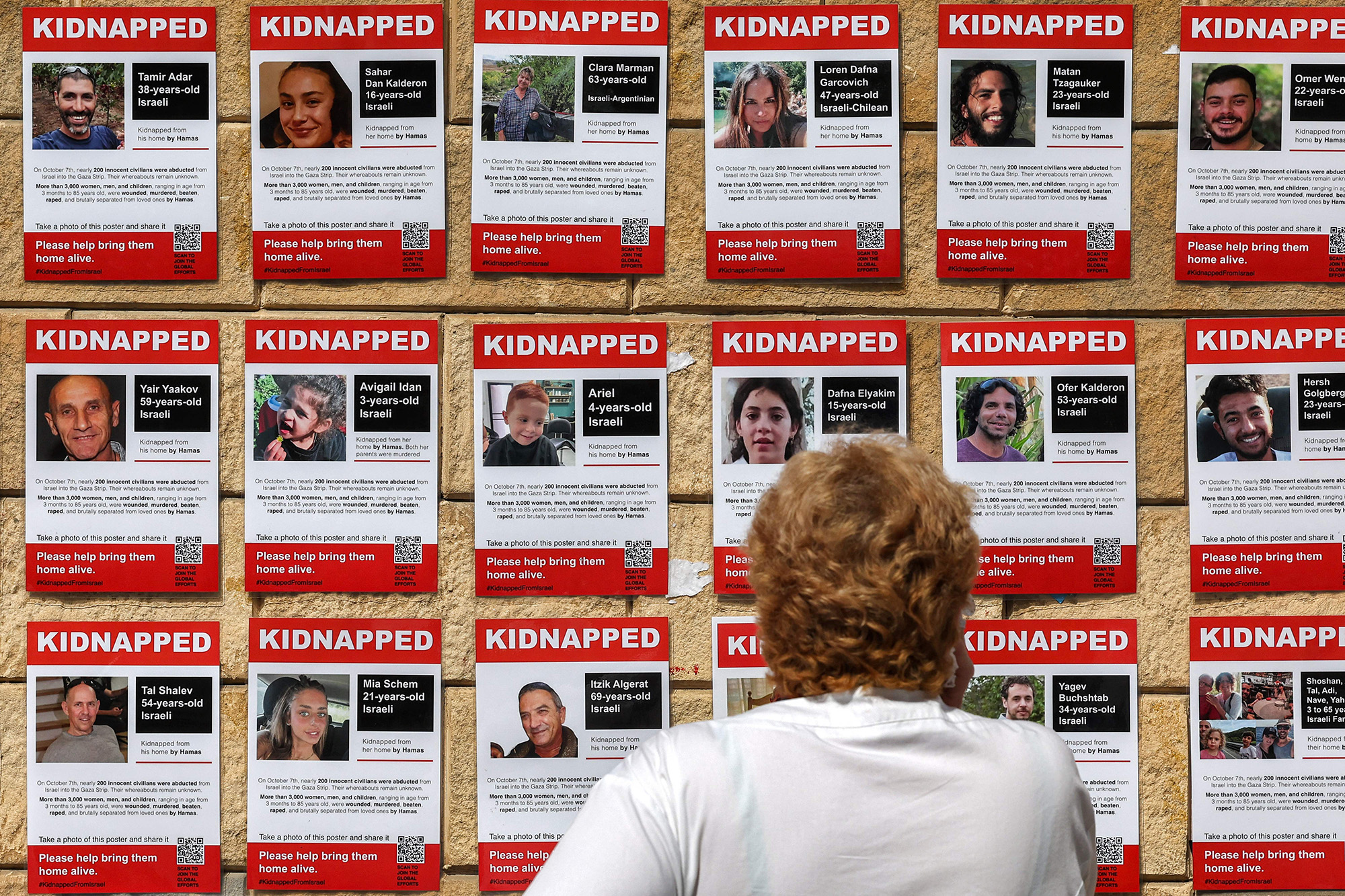 A woman looks at posters showing the pictures of Israeli hostages near Azrieli Mall in Tel Aviv, Israel, on October 18.