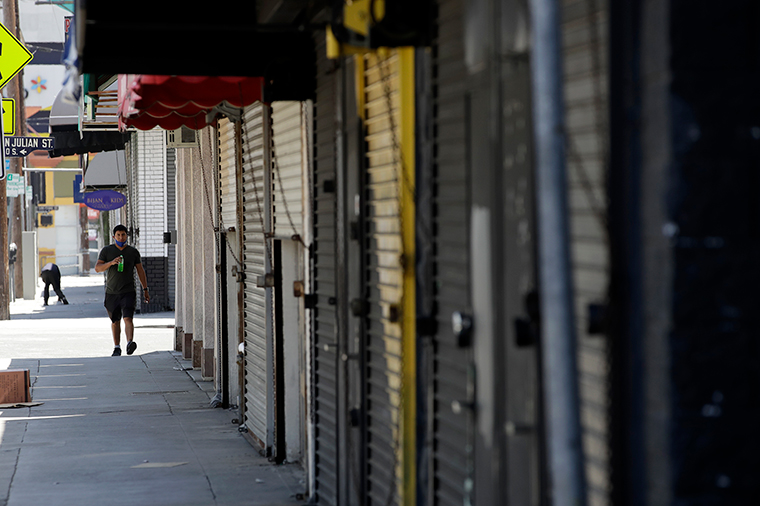 A man walks past closed-off stores Monday, May 4, in the fashion district of Los Angeles. 