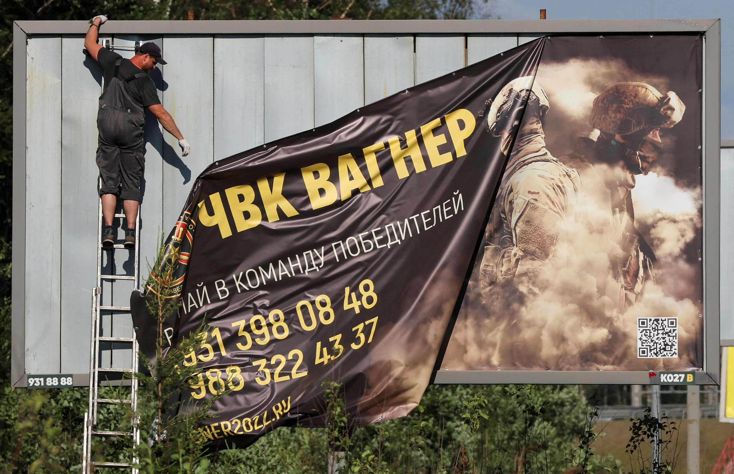 A worker removes an advertising banner promoting service in the Wagner private mercenary group on the outskirts of St. Petersburg, Russia, on Saturday.