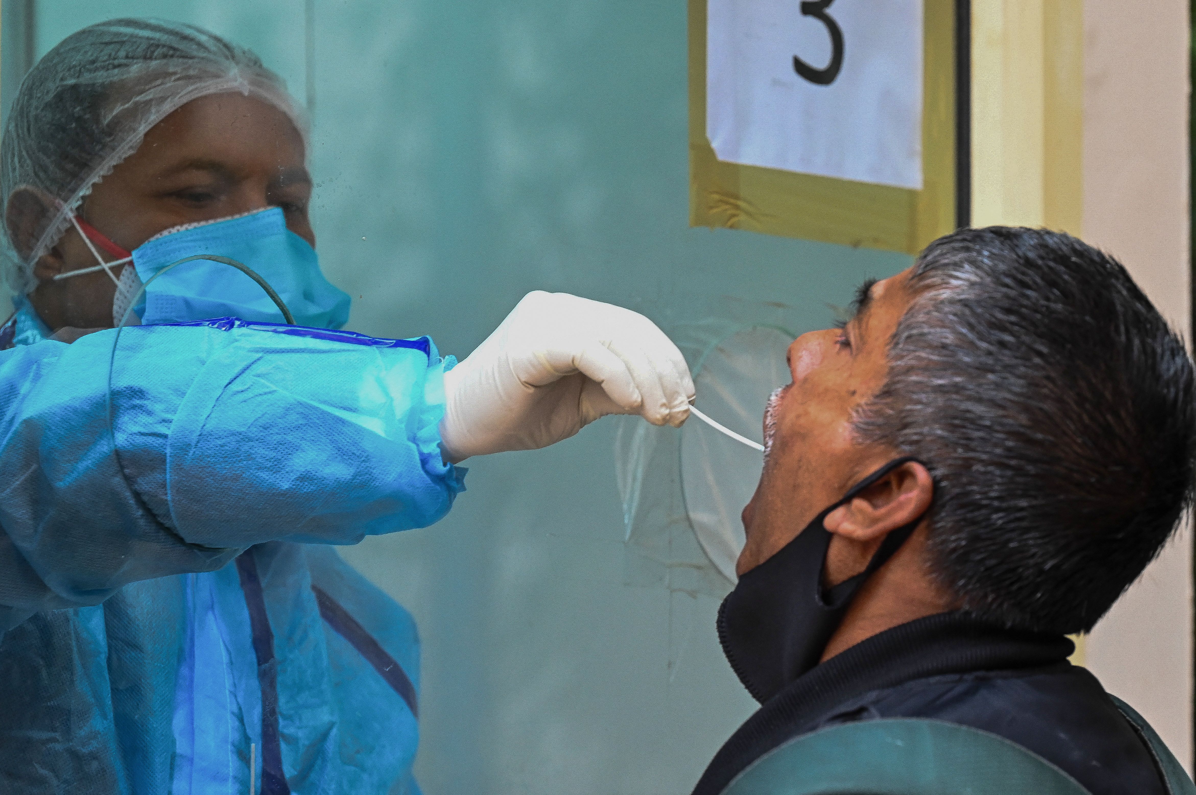A medical worker takes a swab sample from a man for a reverse transcription polymerase chain reaction (RT-PCR) test for the Covid-19 coronavirus at a health centre in New Delhi on January 7, 2022. 