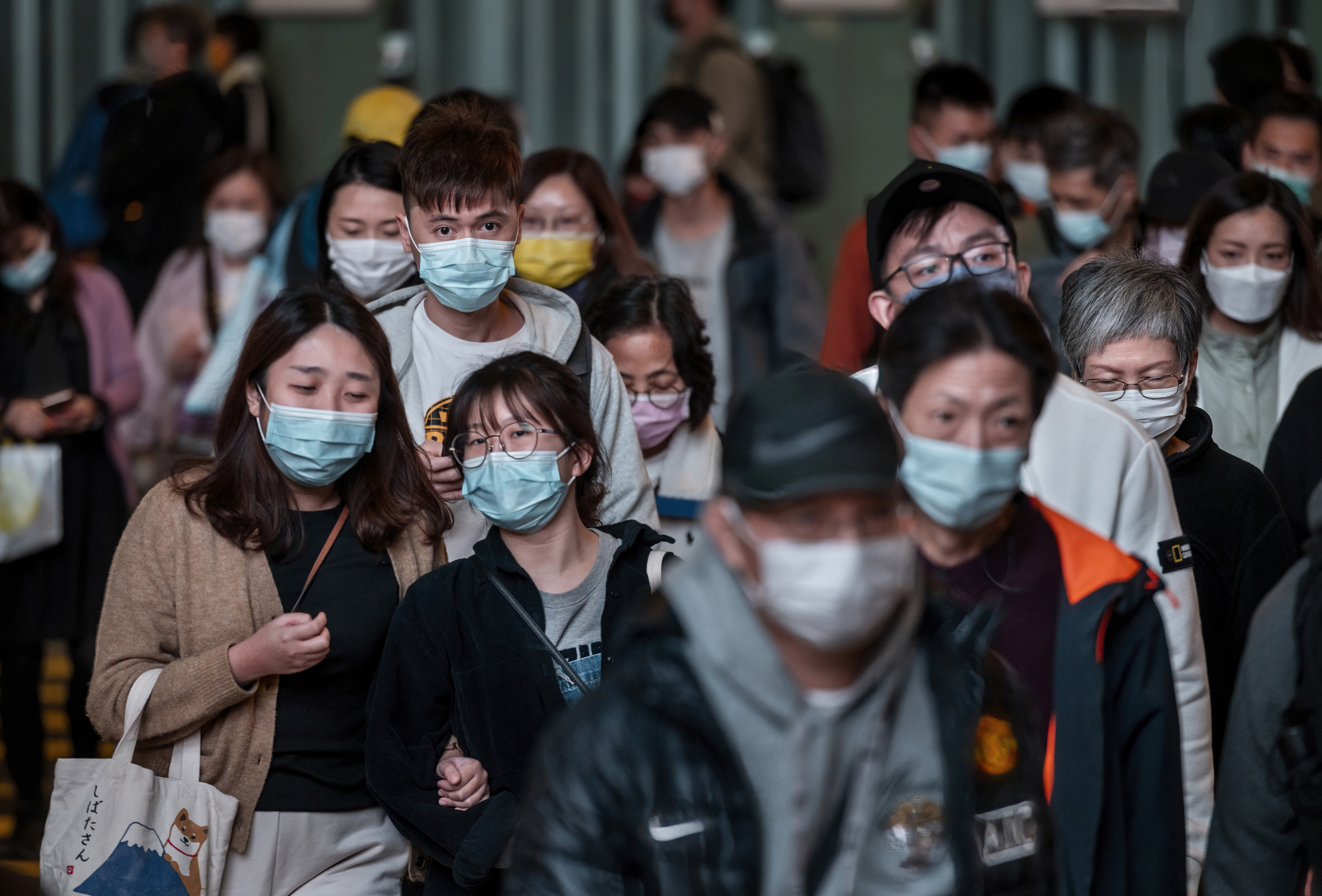 A large crowd of people is seen wearing face masks as a preventive measure against the spread of coronavirus as they walk through a zebra crossing in Hong Kong, China, on 12 December 2021.