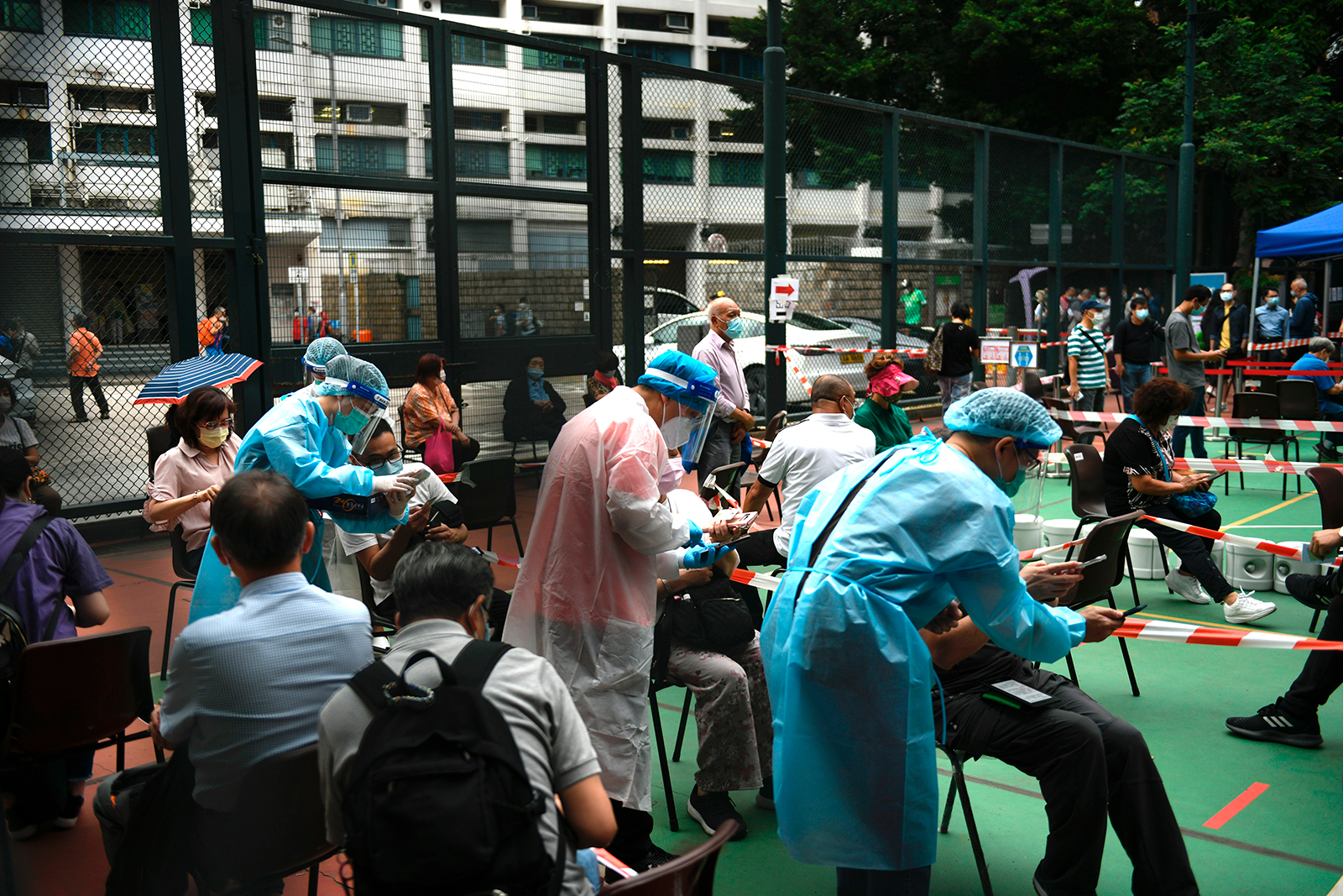 Workers wearing Personal Protection Equipment(PPE) are seen attending to people waiting for a test at a Covid-19 testing center  in Hong Kong, on November 24.