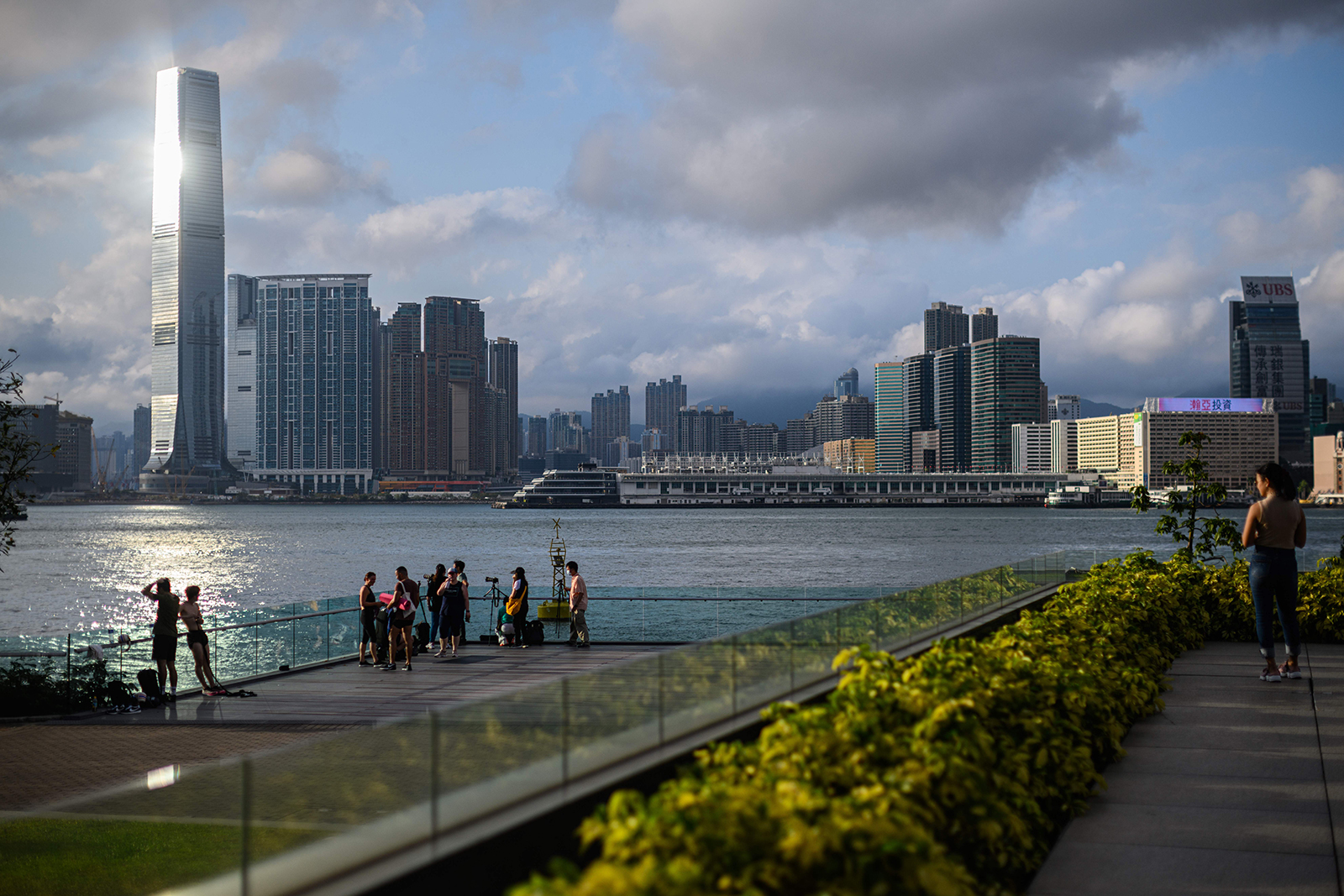 People gather on a clear day as they stand on a viewing platform in Tamar Park overlooking Victoria Harbour and the Kowloon skyline in Hong Kong on Tuesday, May 5.